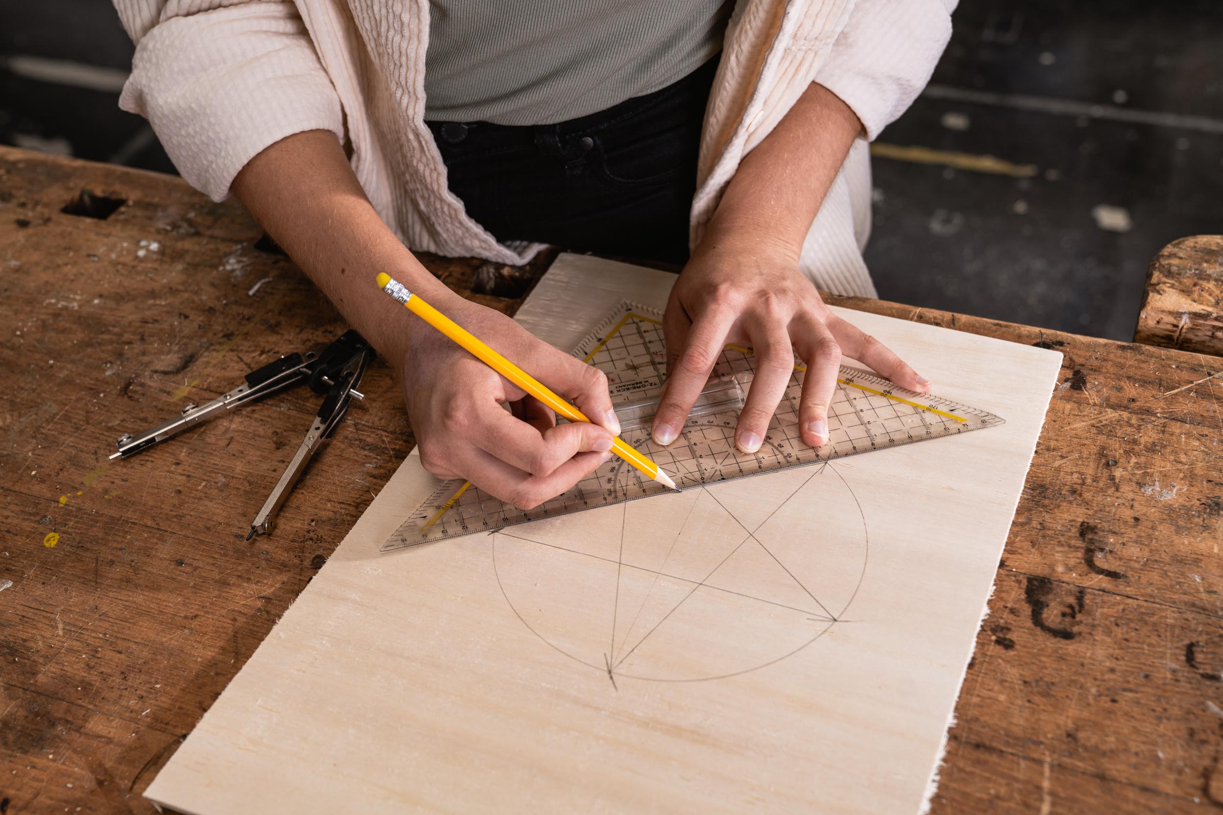 Egy rétegelt lemezlapon különböző pontokat kötnek össze egy háromszögű vonalzó segítségével úgy, hogy egy csillag szülessen belőle.