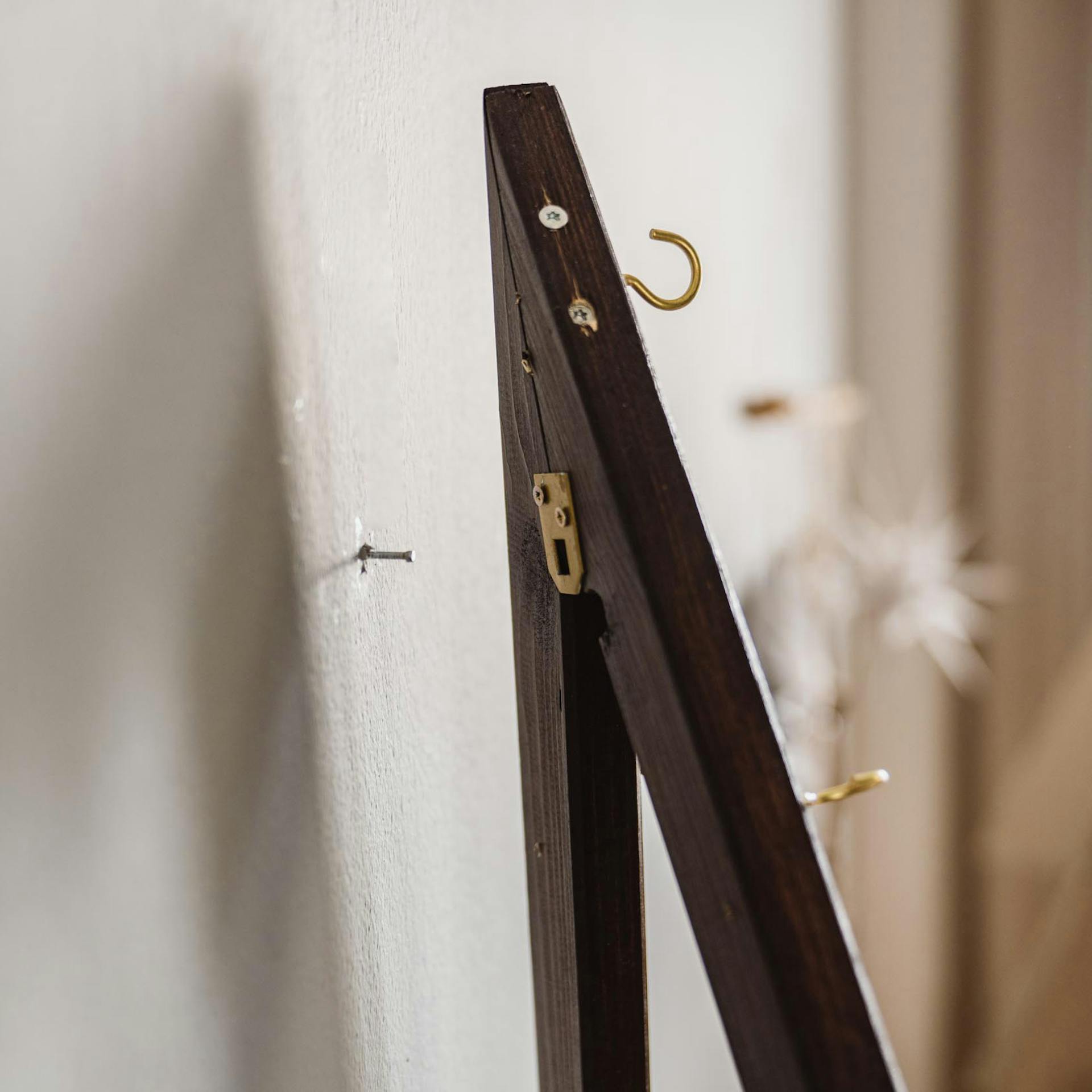 Handwerkerin hängt den Rahmen des Wandbaums an der Wand auf.