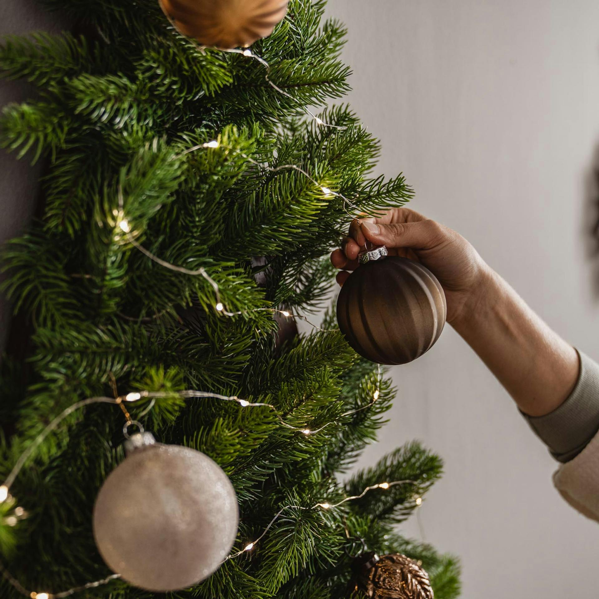 Handwerkerin dekoriert den Wandbaum mit Christbaumkugeln.