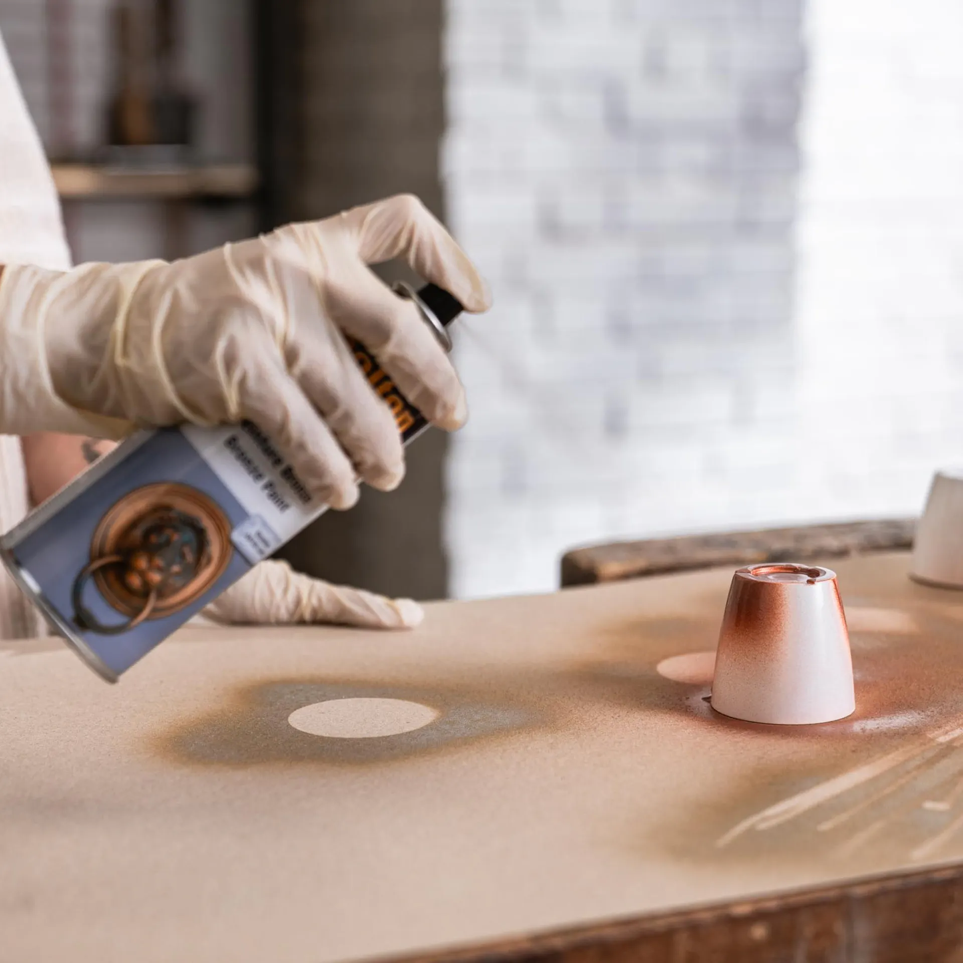 Aranyszínű festékszóróval fújják le a poharakat.