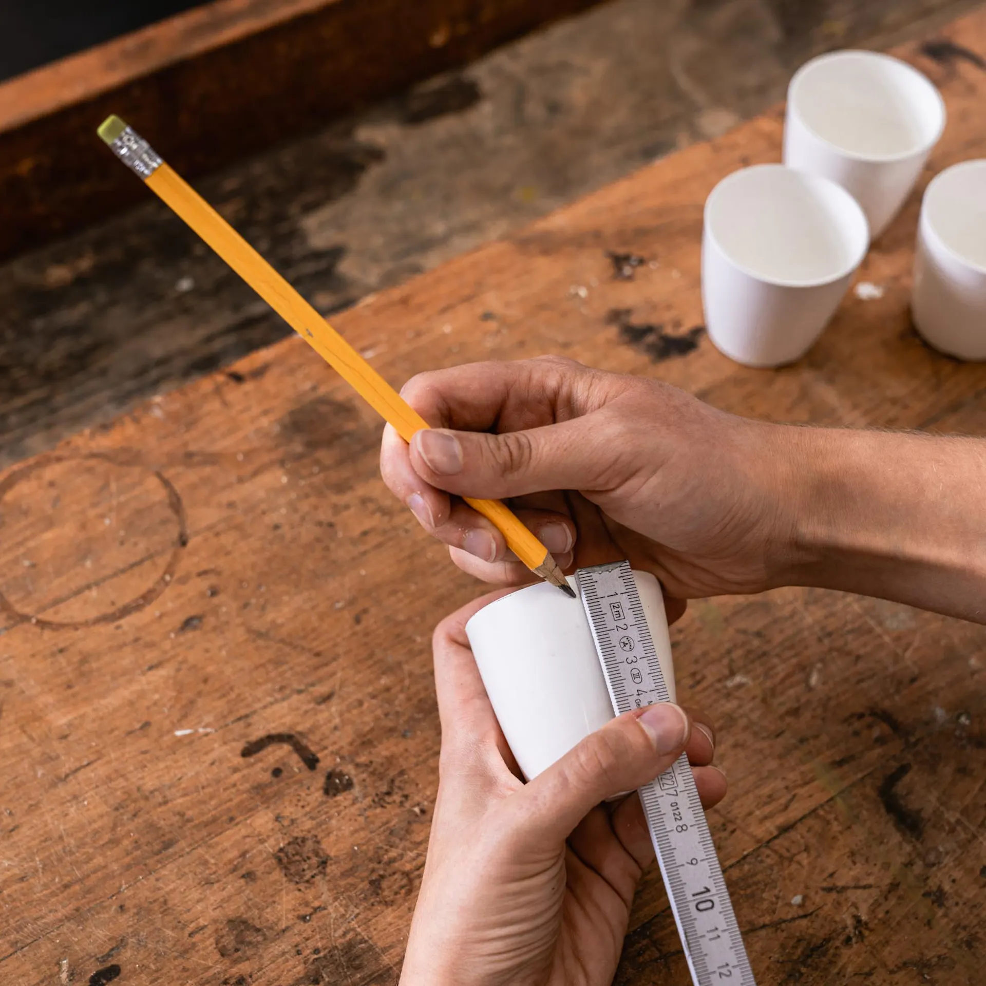 Ceruzával és vonalzóval jelet tesznek egy pohárra.