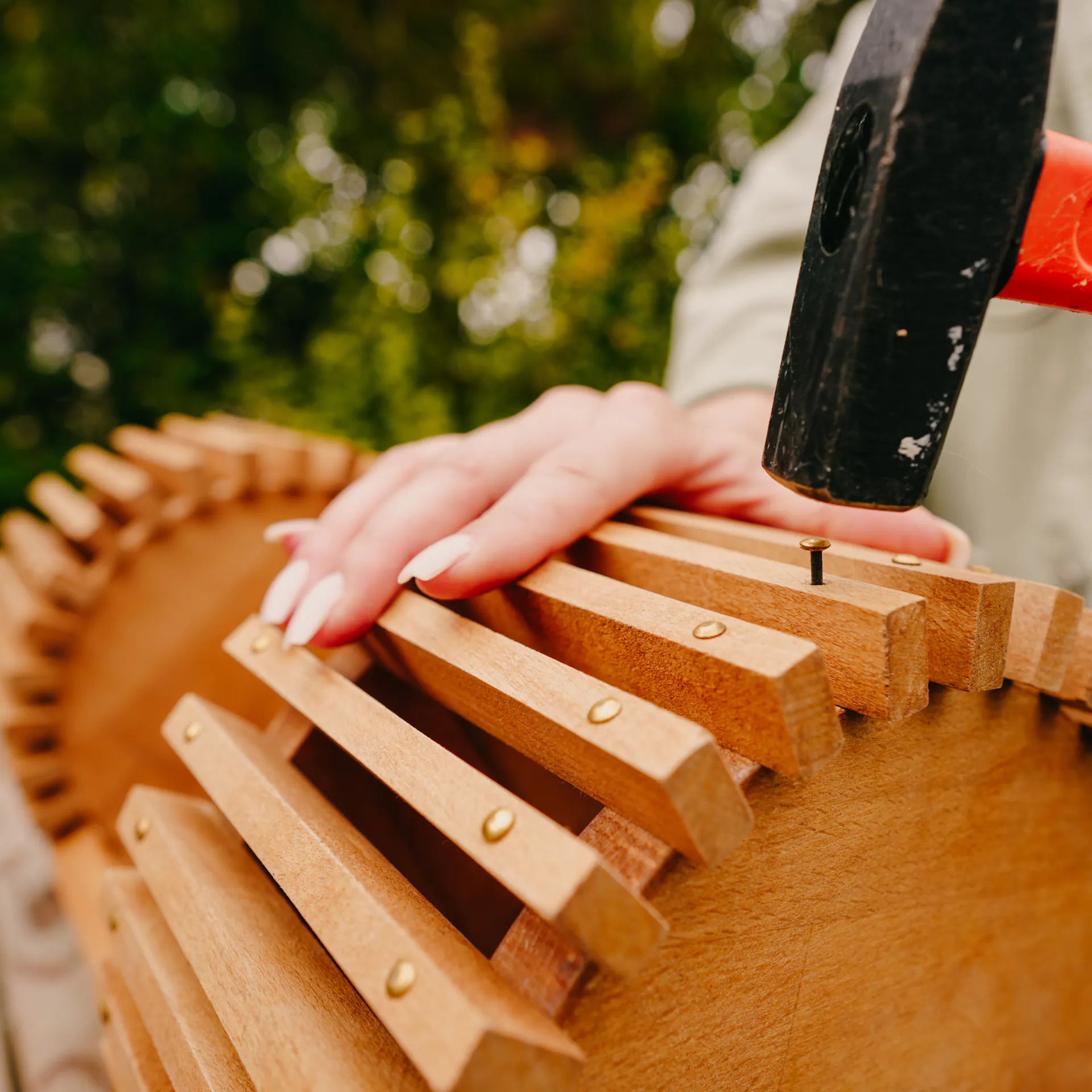 Řemeslnice upevňuje krátké lišty pomocí kladiva a hřebíků