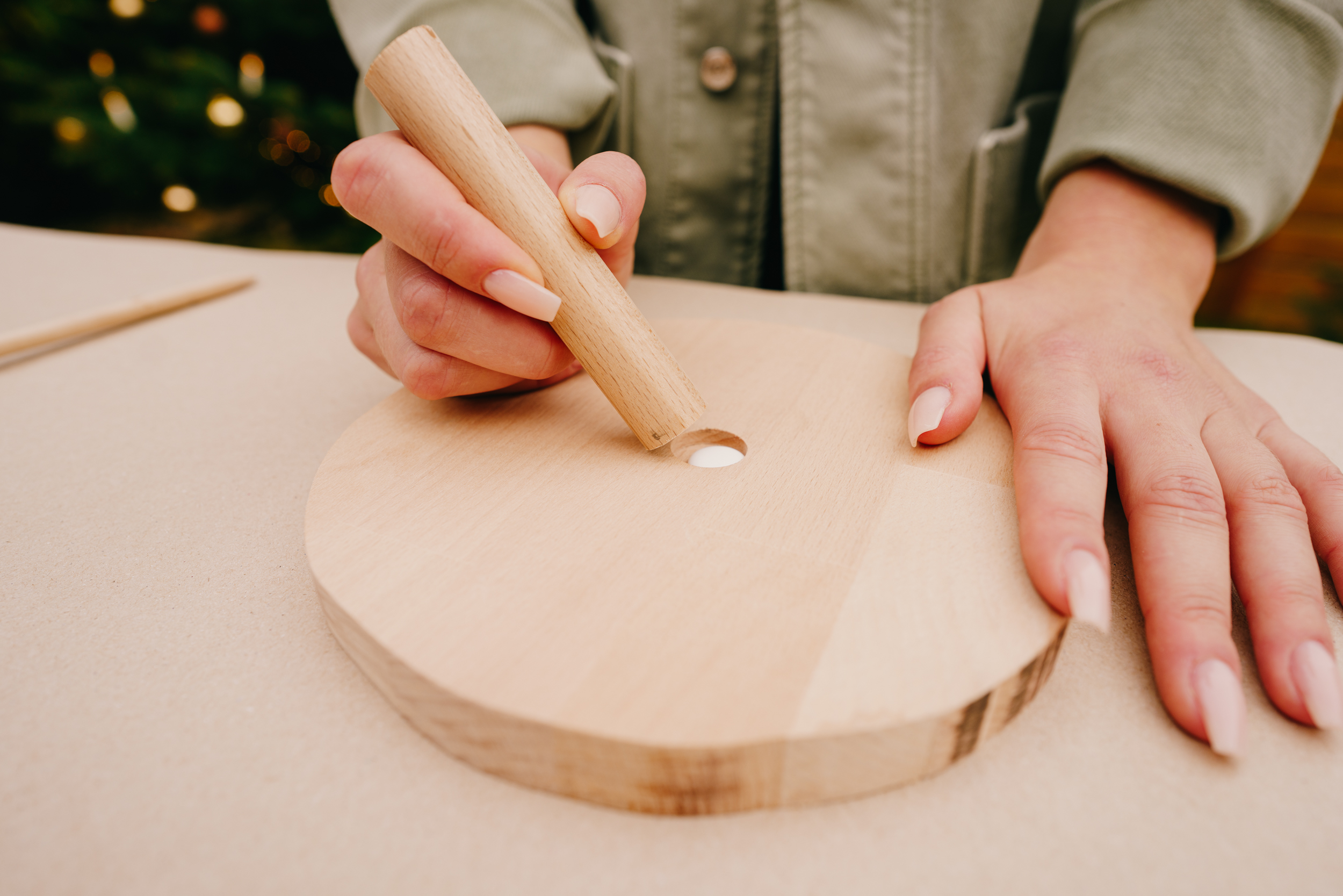 Řemeslnice vsazuje kulatou tyč do předvrtaného otvoru