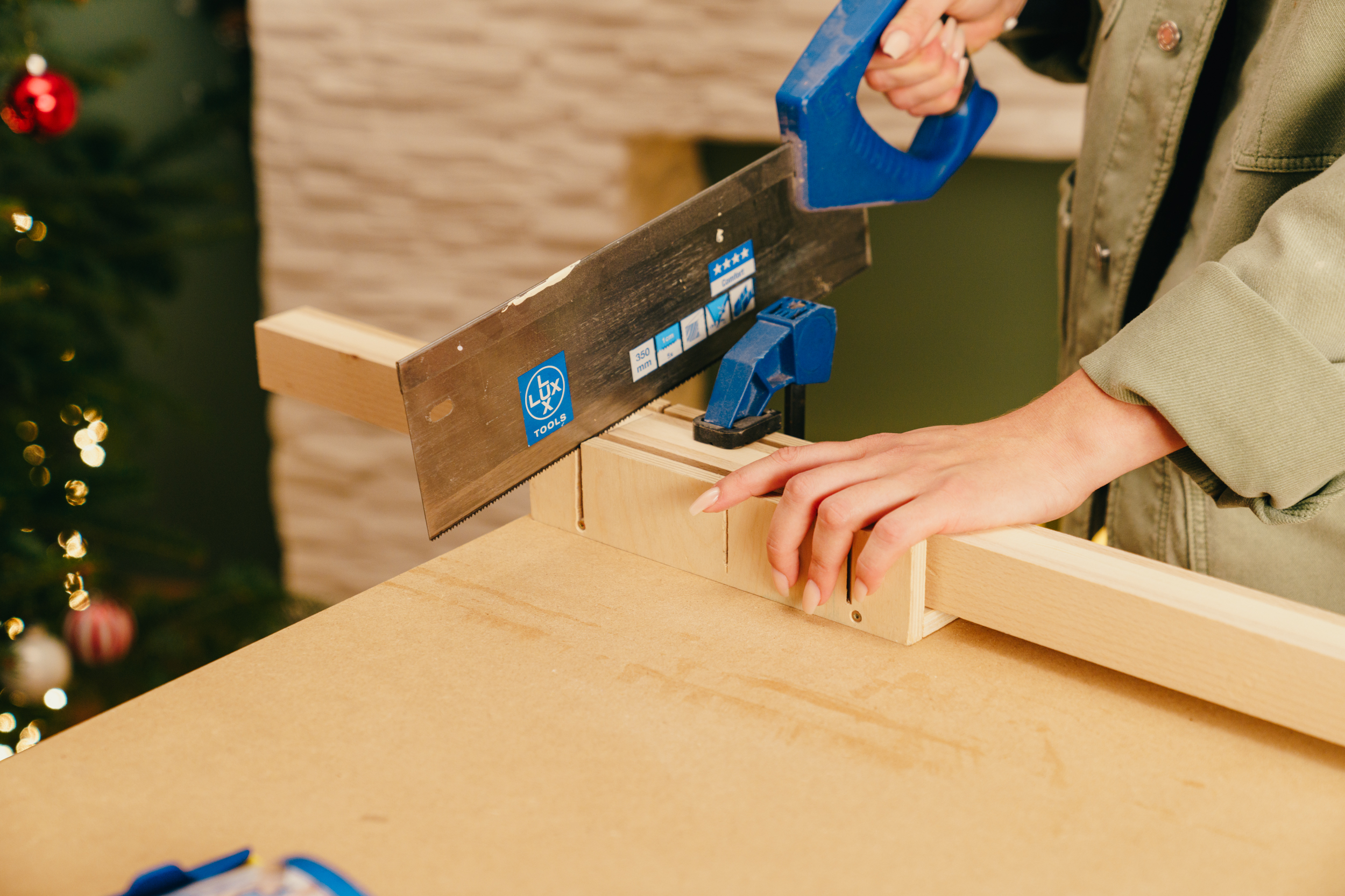 Egy barkácsoló méretre vágja a léceket egy gérvágó doboz segítségével.