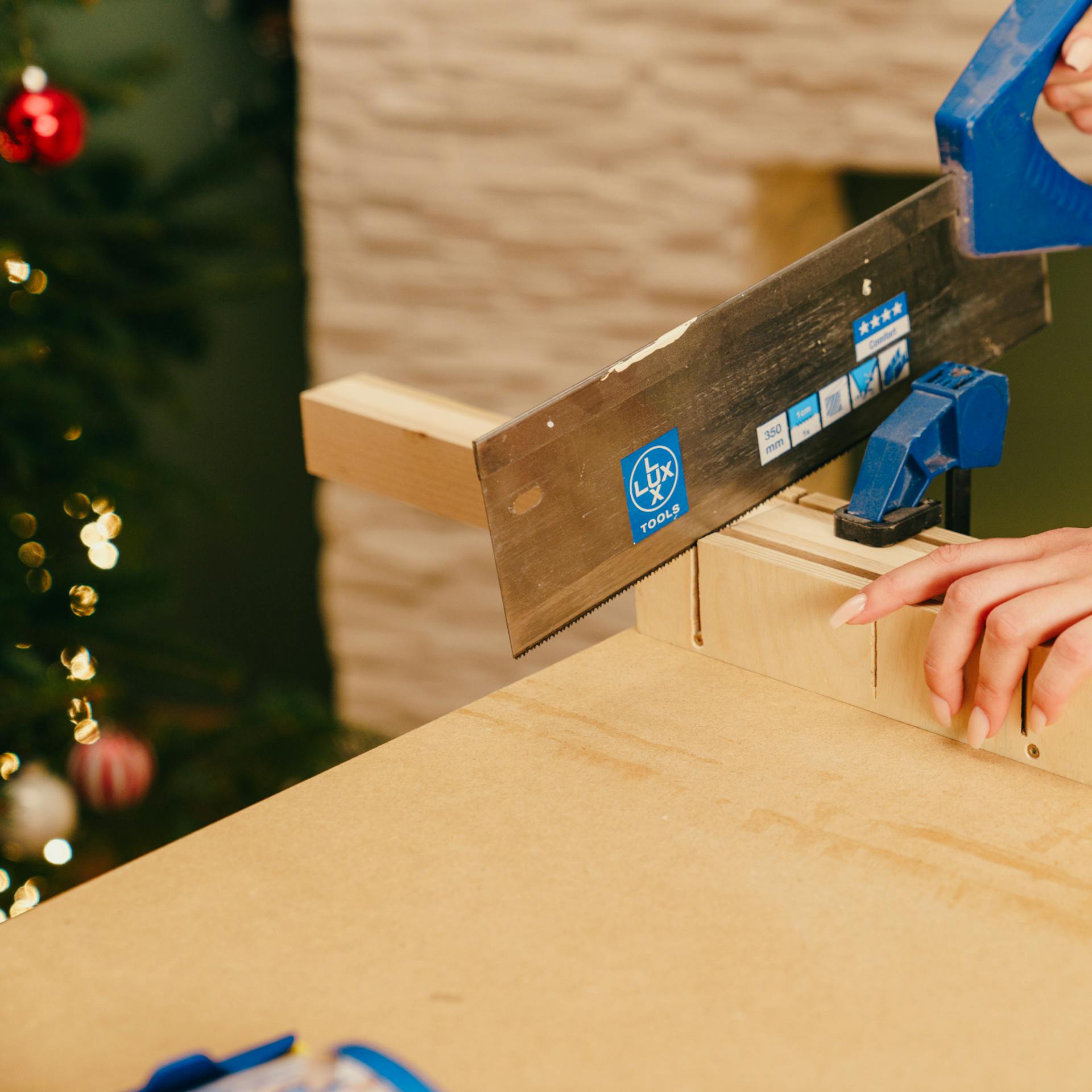 Egy barkácsoló méretre vágja a léceket egy gérvágó doboz segítségével.