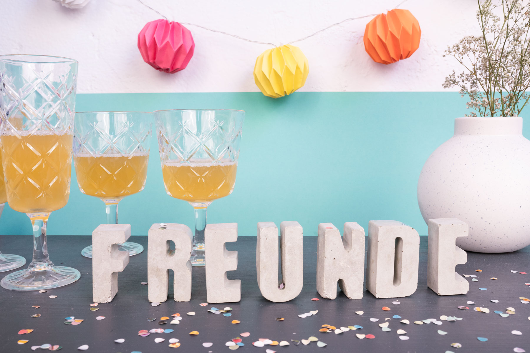 Betonbuchstaben mit Partyaccessoires als Tischdeko