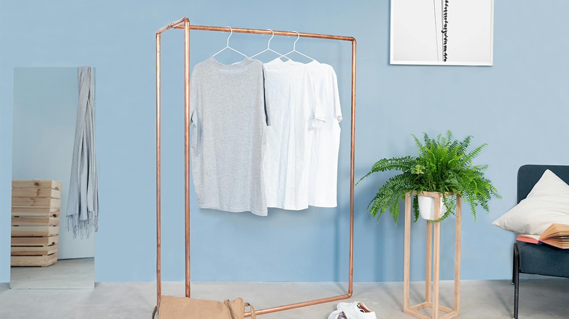 Kupferfarbener Garderobenständer vor blauer Wand
