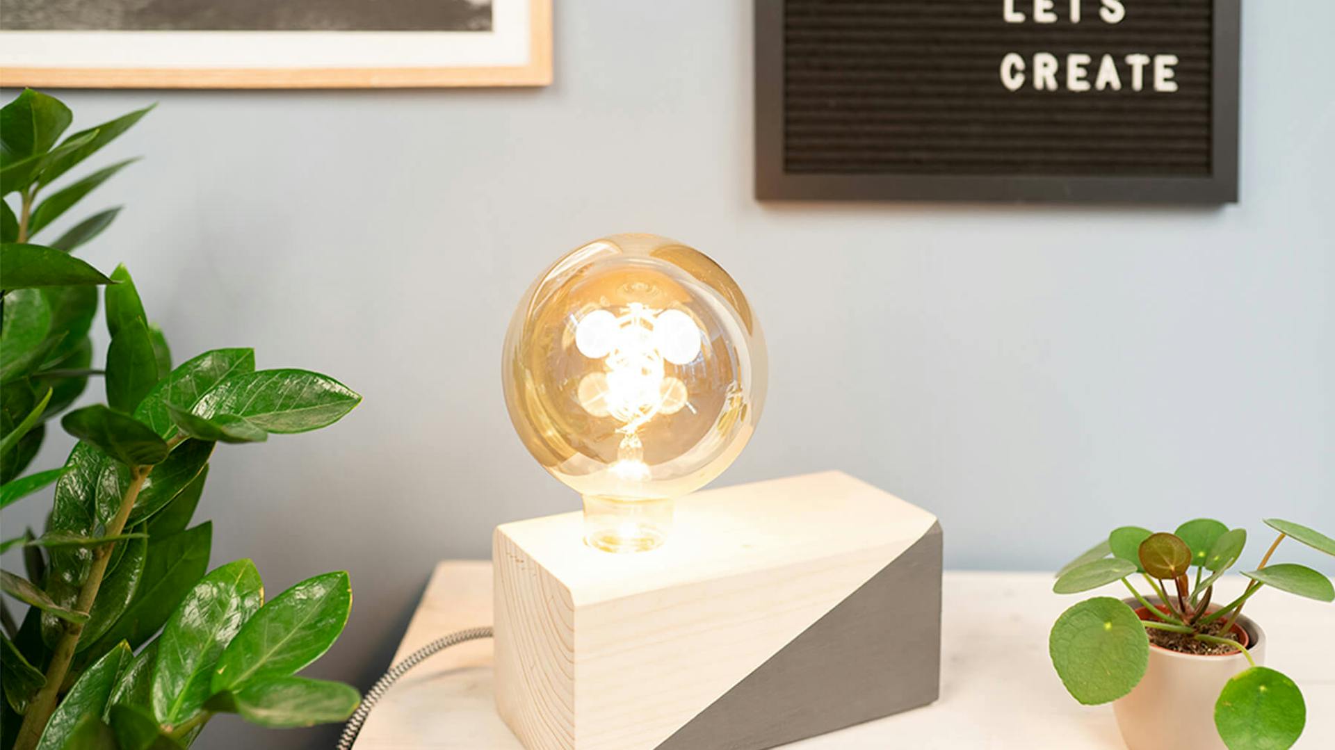 Eine selbstgebaute Tischleuchte aus Holz mit großer Glühbirne.