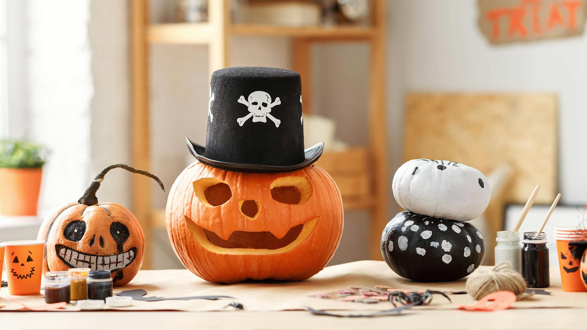 Kürbisse mit aufgemalten und geschnitzten Kürbisgesichtern auf einem Tisch