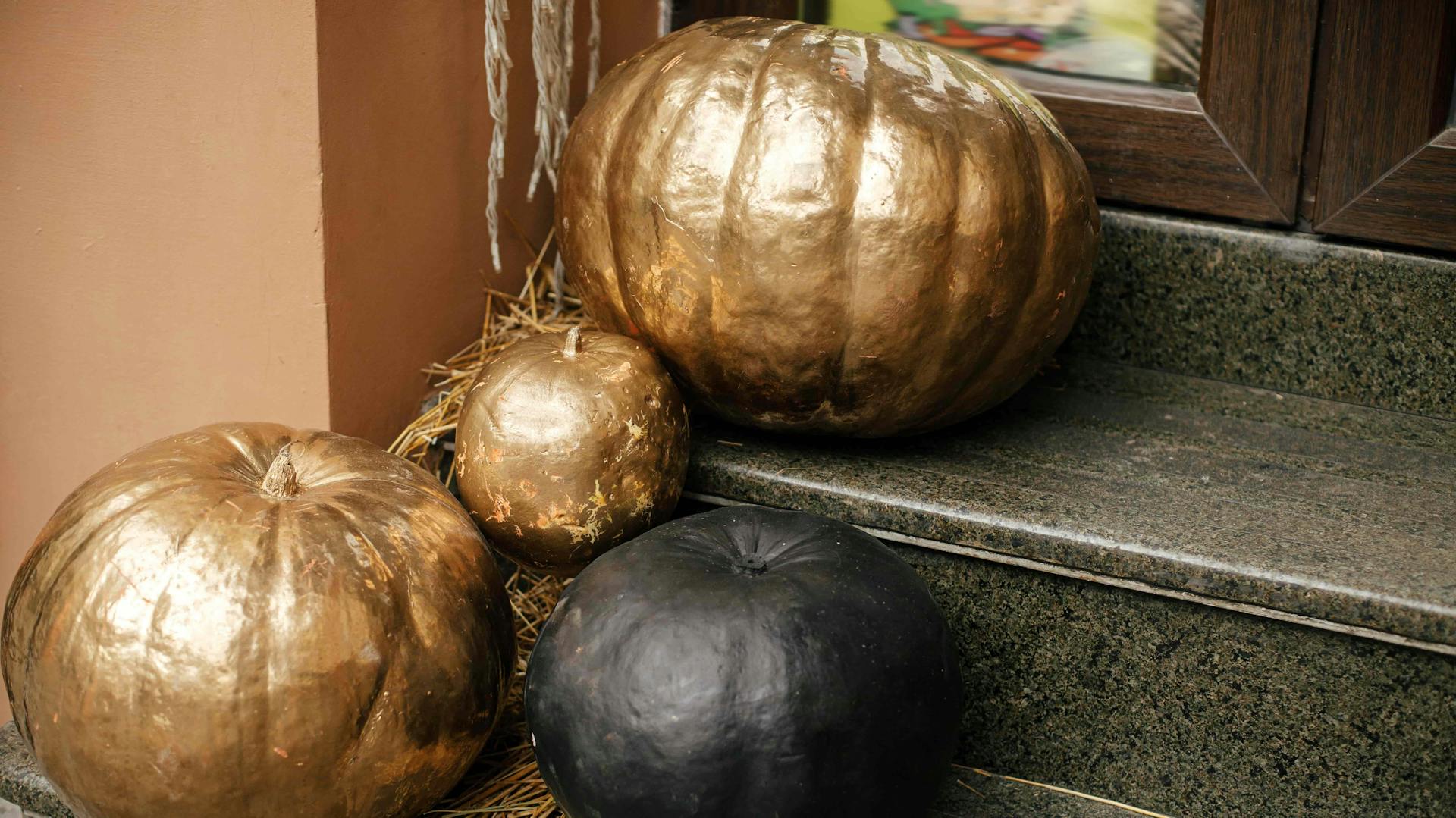 Schwarz und gold bemalte Kürbisse auf einer Treppe.