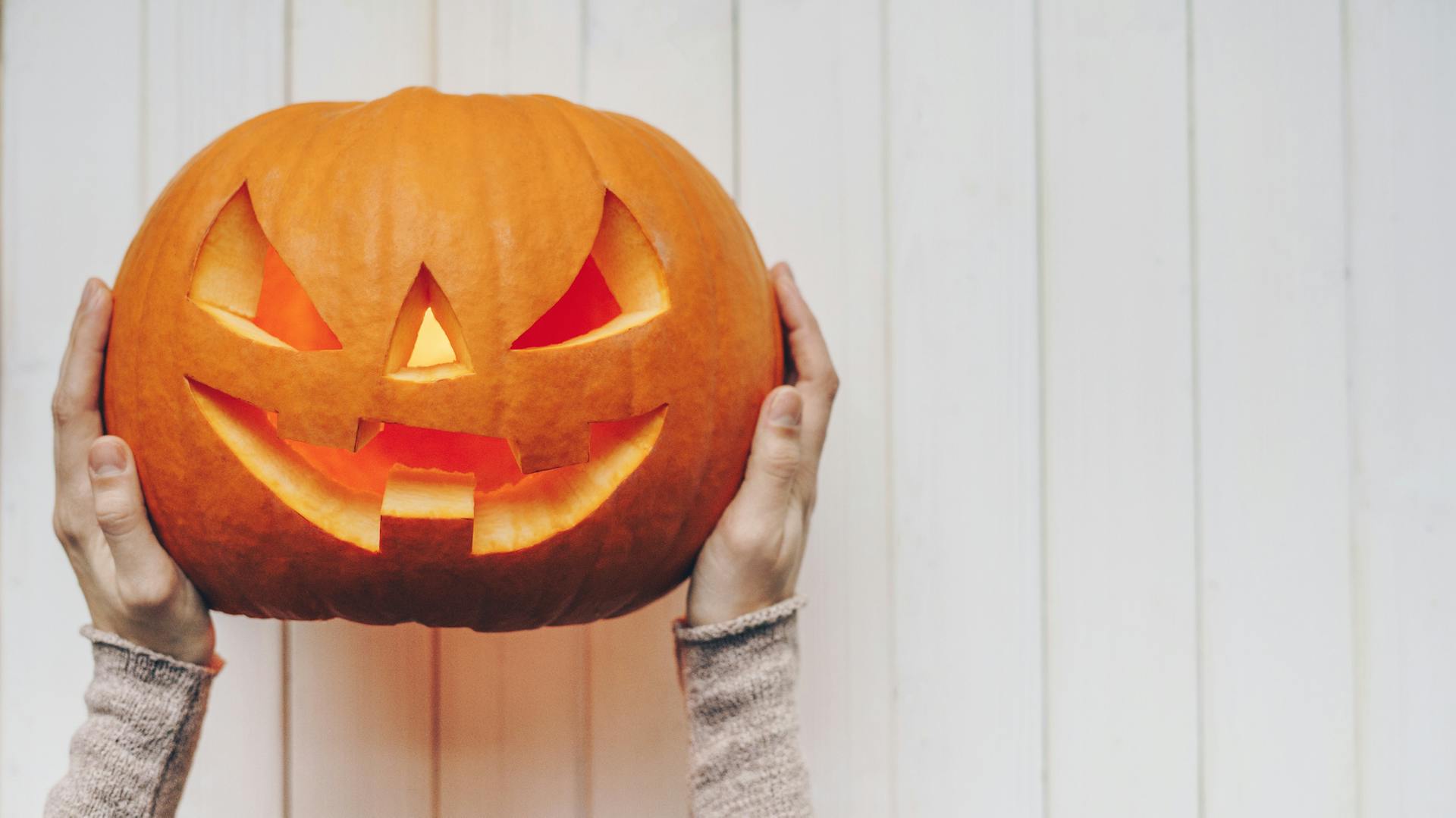 Egy nő faragott tököt tart a kezében.