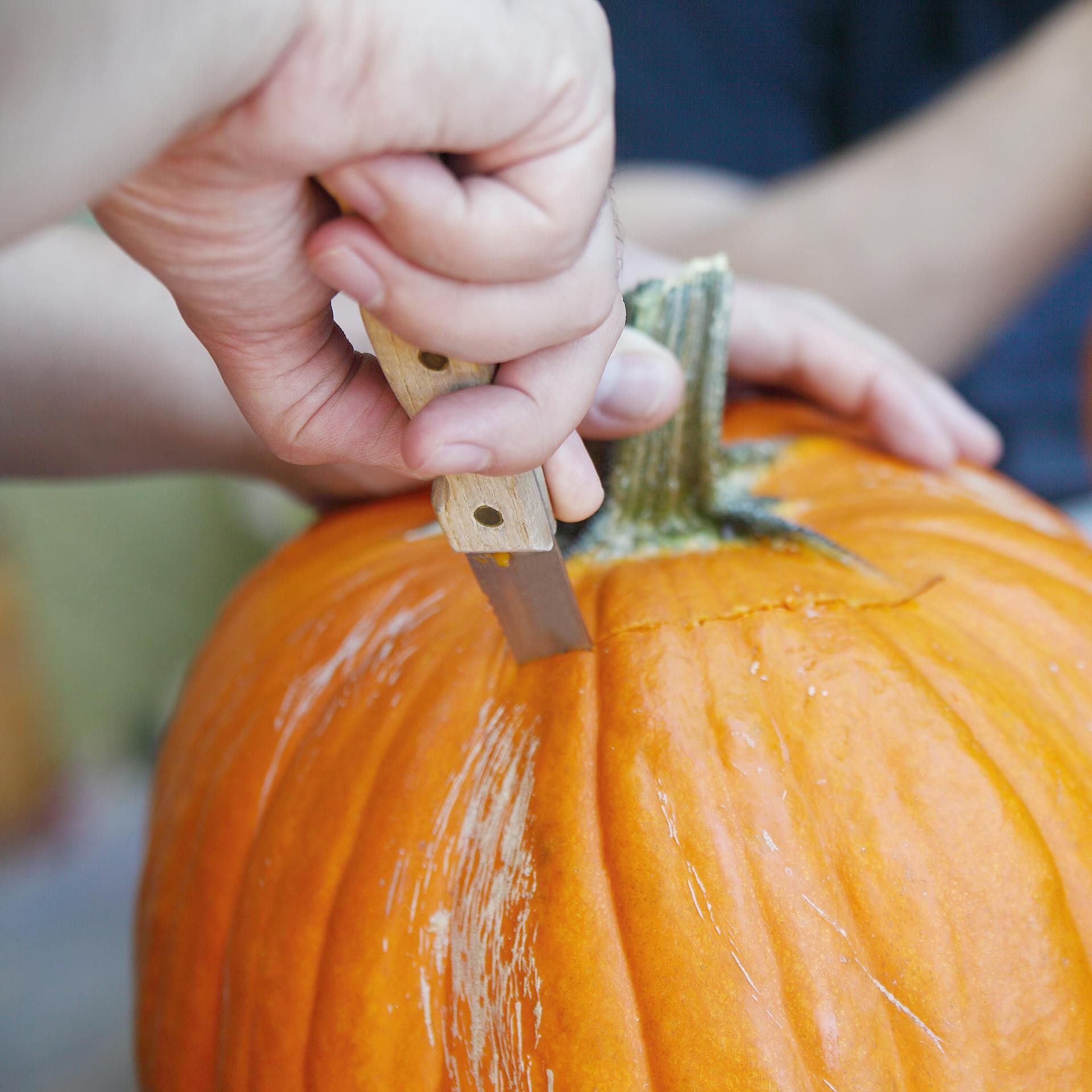 Qualcuno sta tagliando via la calotta di una zucca.