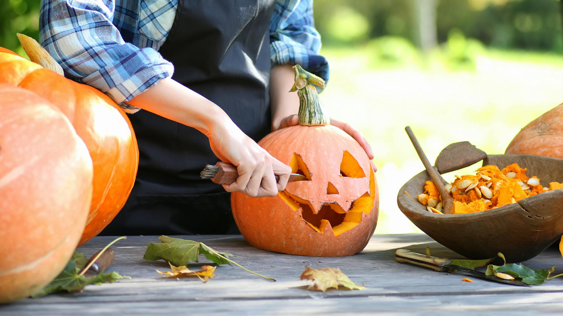 Eine Frau schnitzt einen Kürbis.