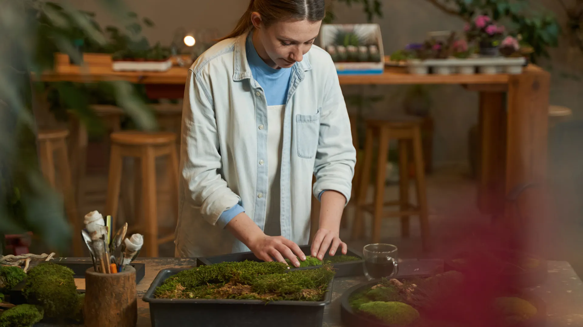 Domácí kutilka vyrábí na pracovním stole kulatý mechový obraz