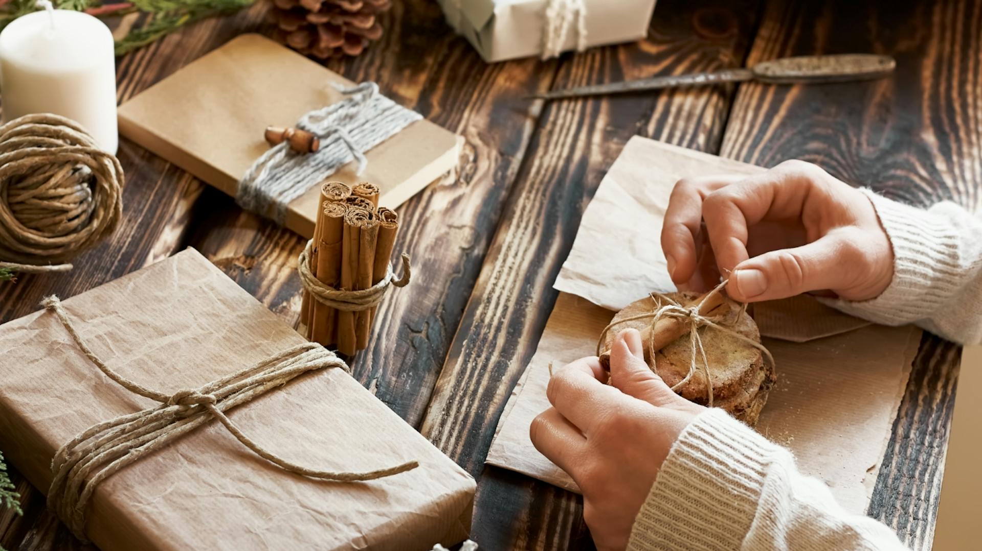 Eine Person verpackt Geschenke in braunem Papier.