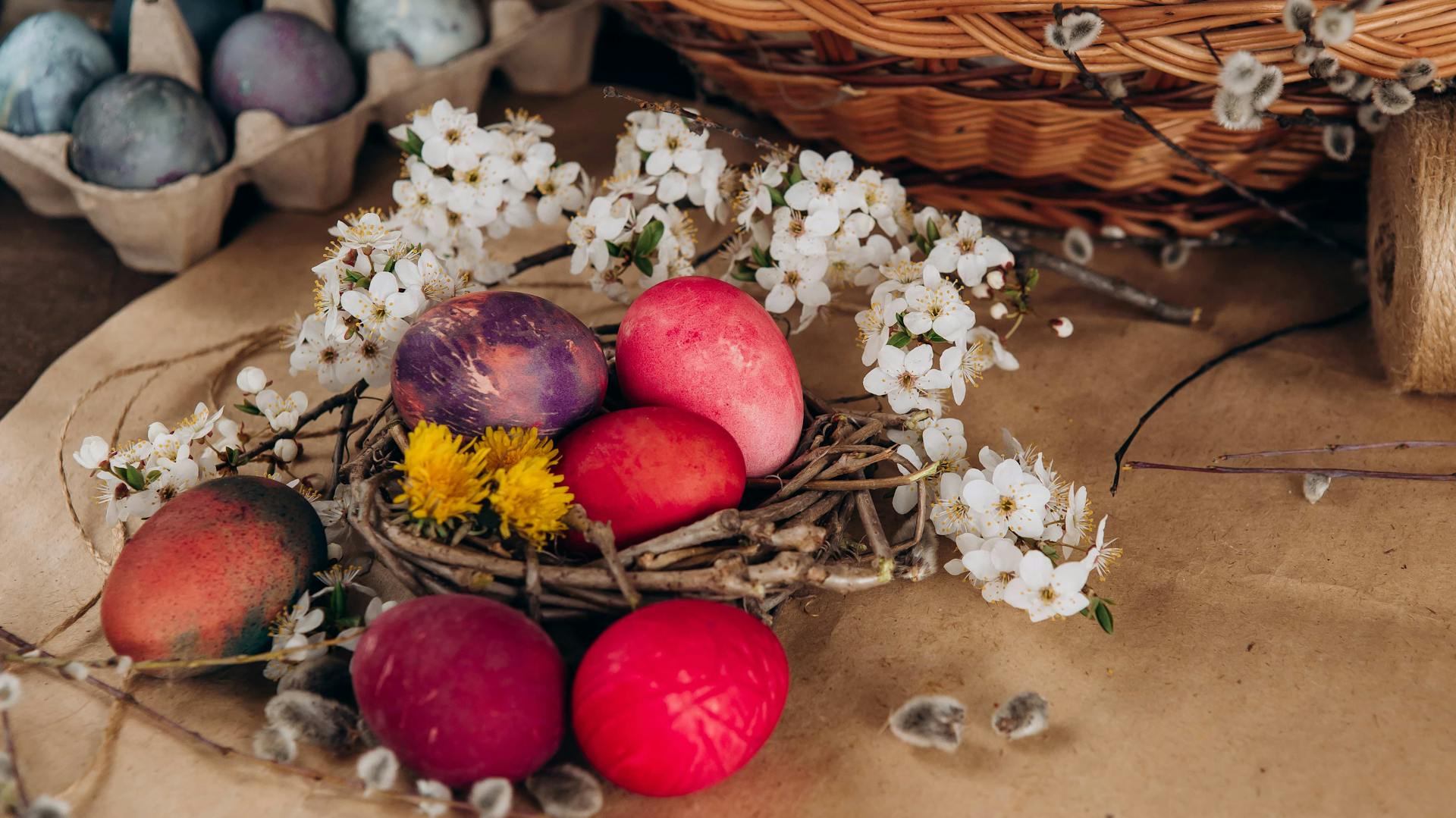 Ein selbst gebasteltes Osternest mit gefärbten Eiern und Blumen
