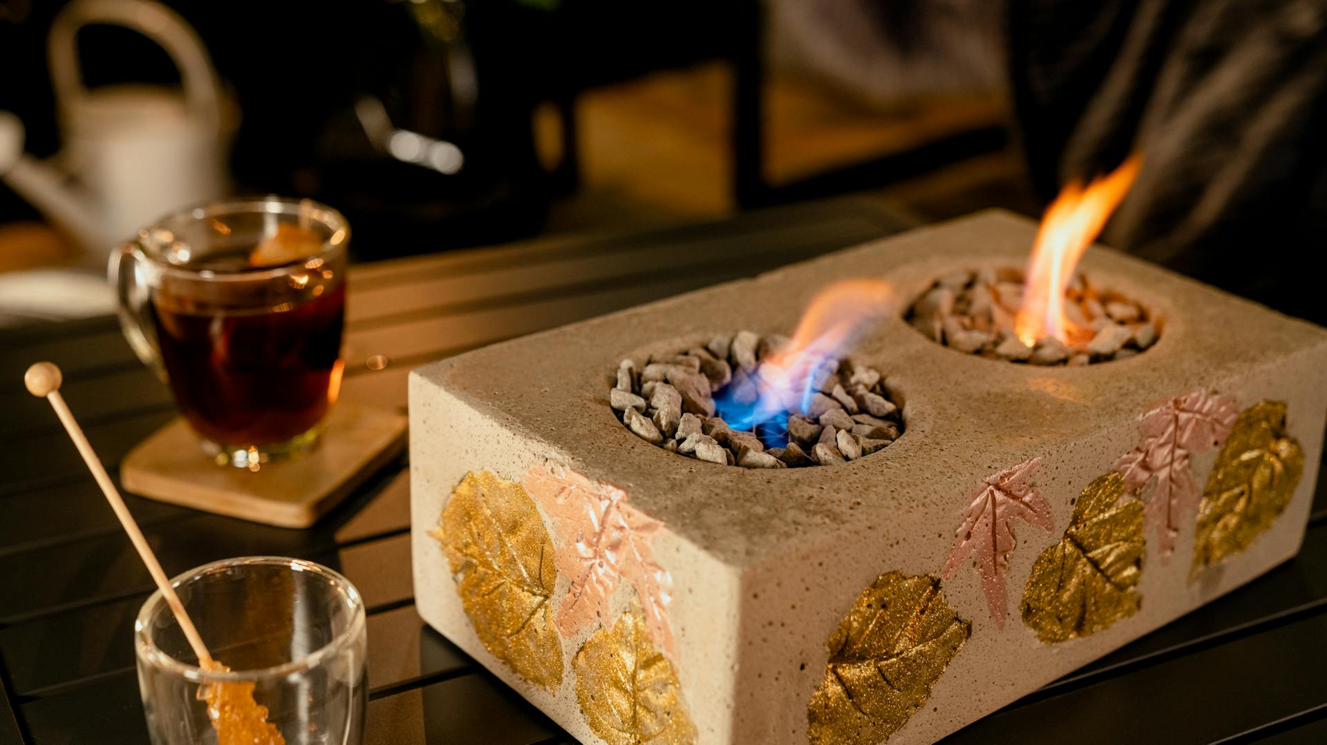 Angezündeter Tischkamin neben Teeglas