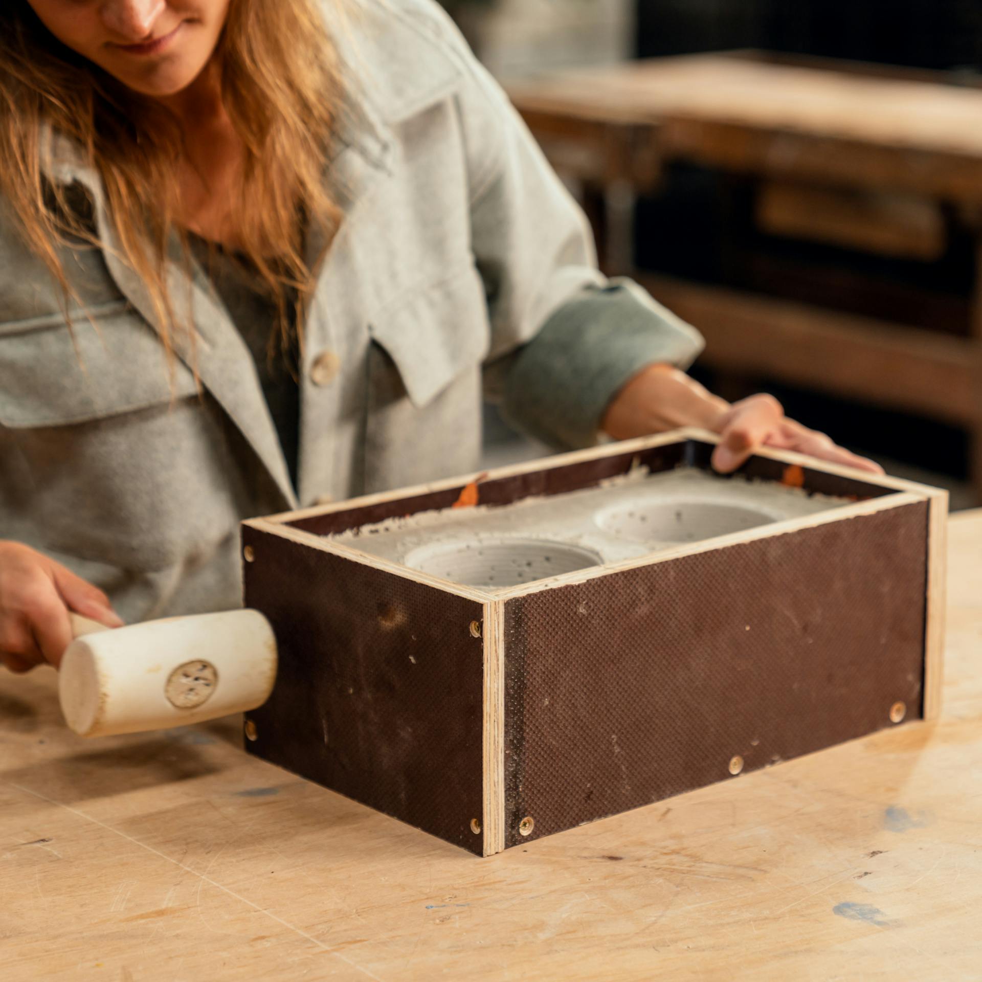 Kalapáccsal ütögetnek egy betonnal teli fadobozt