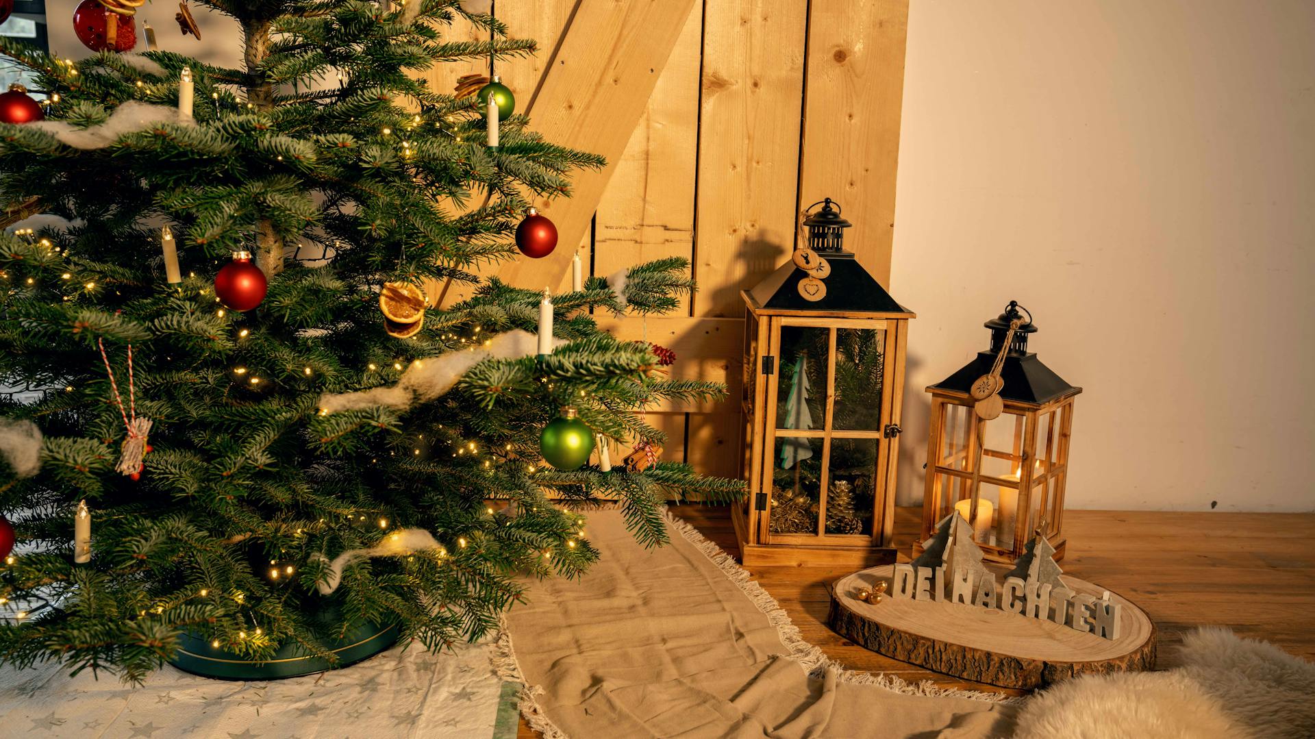 Albero di Natale allestito su coperta accanto a delle lanterne