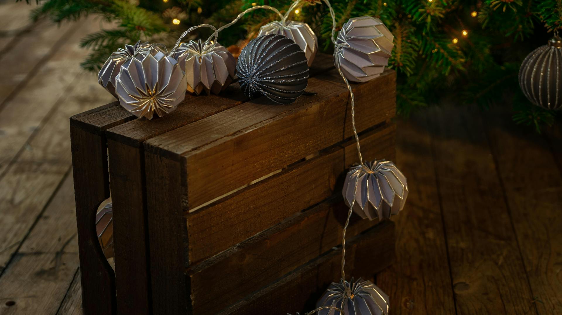 Szép, kék-ezüst karácsonyfadíszek a fényfüzérrel díszített fa előtt