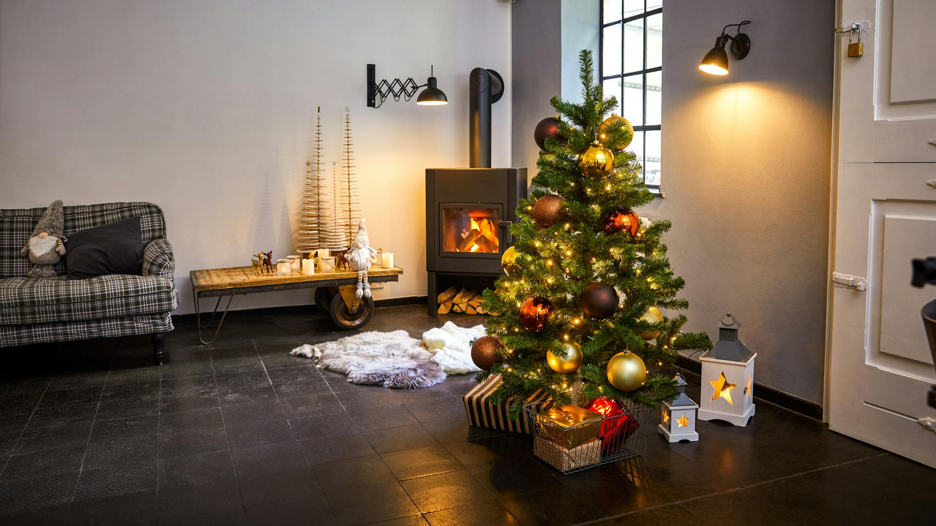 Geschmückter Weihnachtsbaum mit großen Kugeln in gemütlichem Wohnzimmer vor Kamin