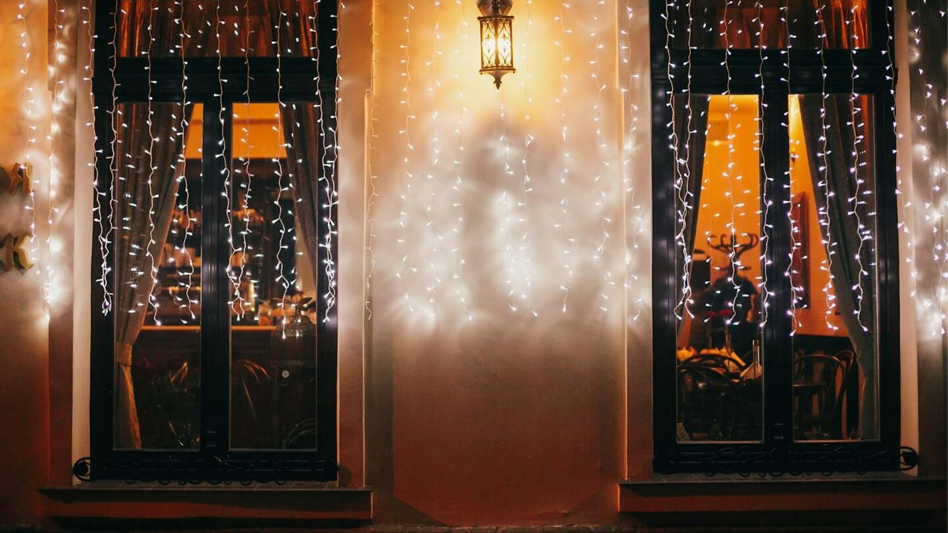 Zwei Fenster mit Vorhang aus Lichterketten.
