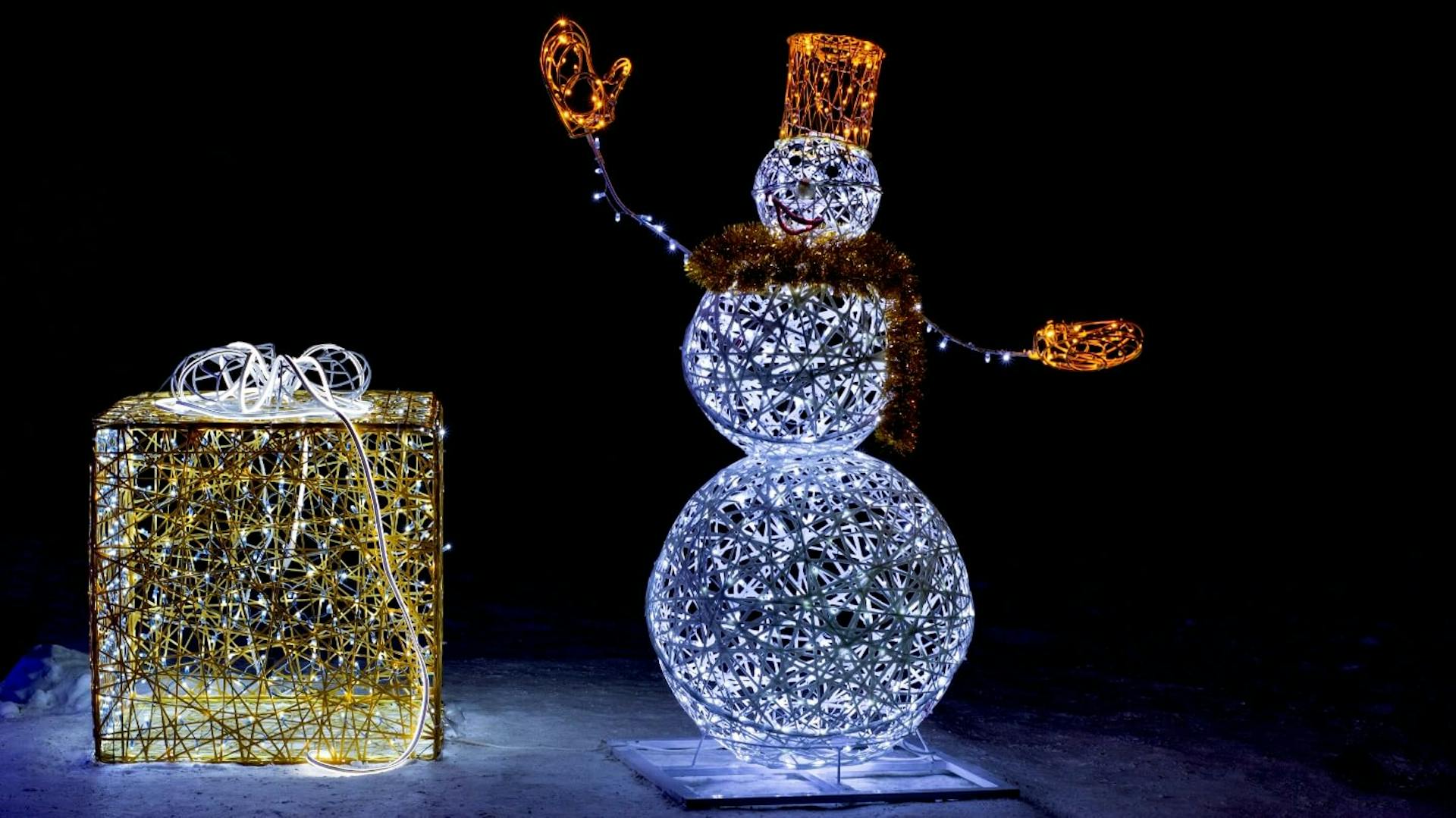 Ein Schneemann und ein Geschenk als Leuchtfiguren.