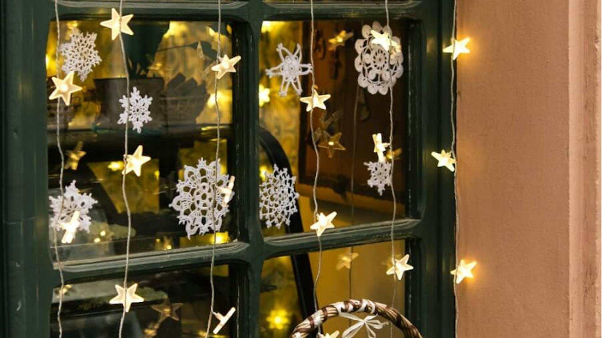 Fenster mit grünem Rahmen verziert mit einer Lichterkette.