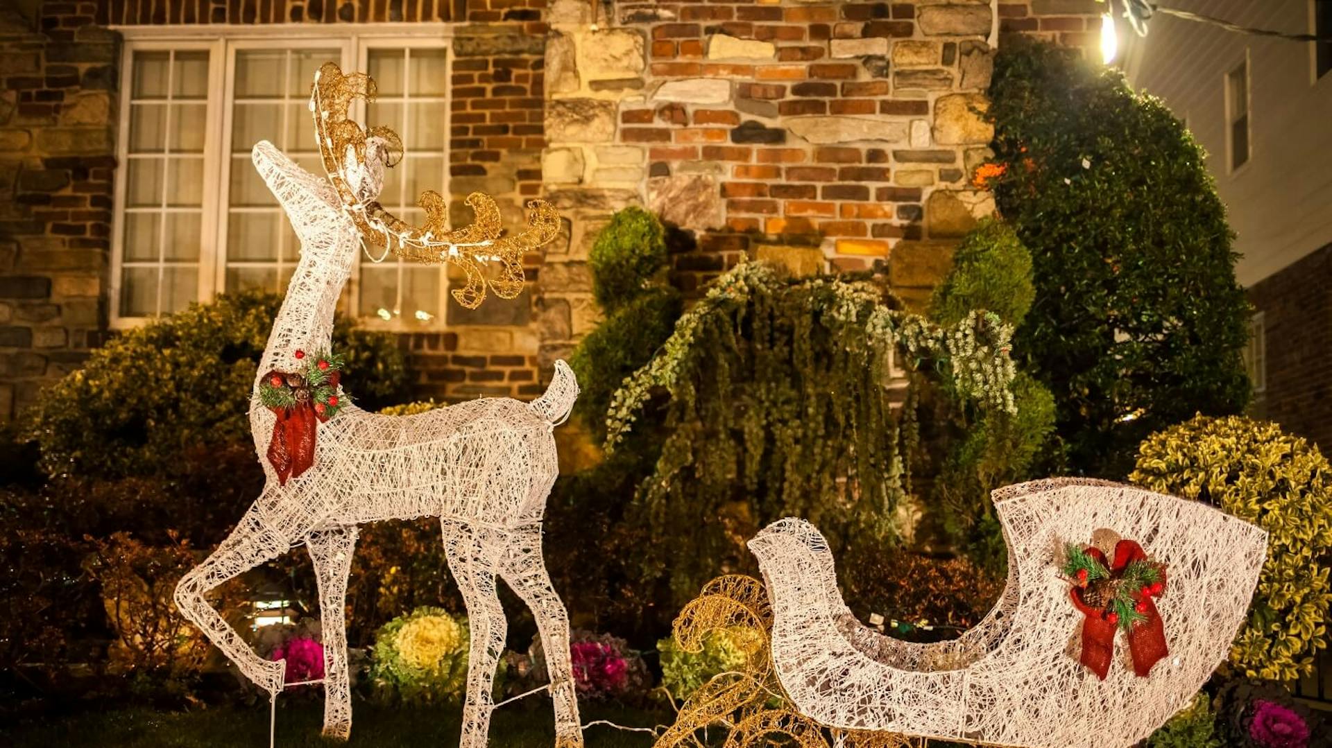 Rentier mit Schlitten als Leuchtfigur im Garten.