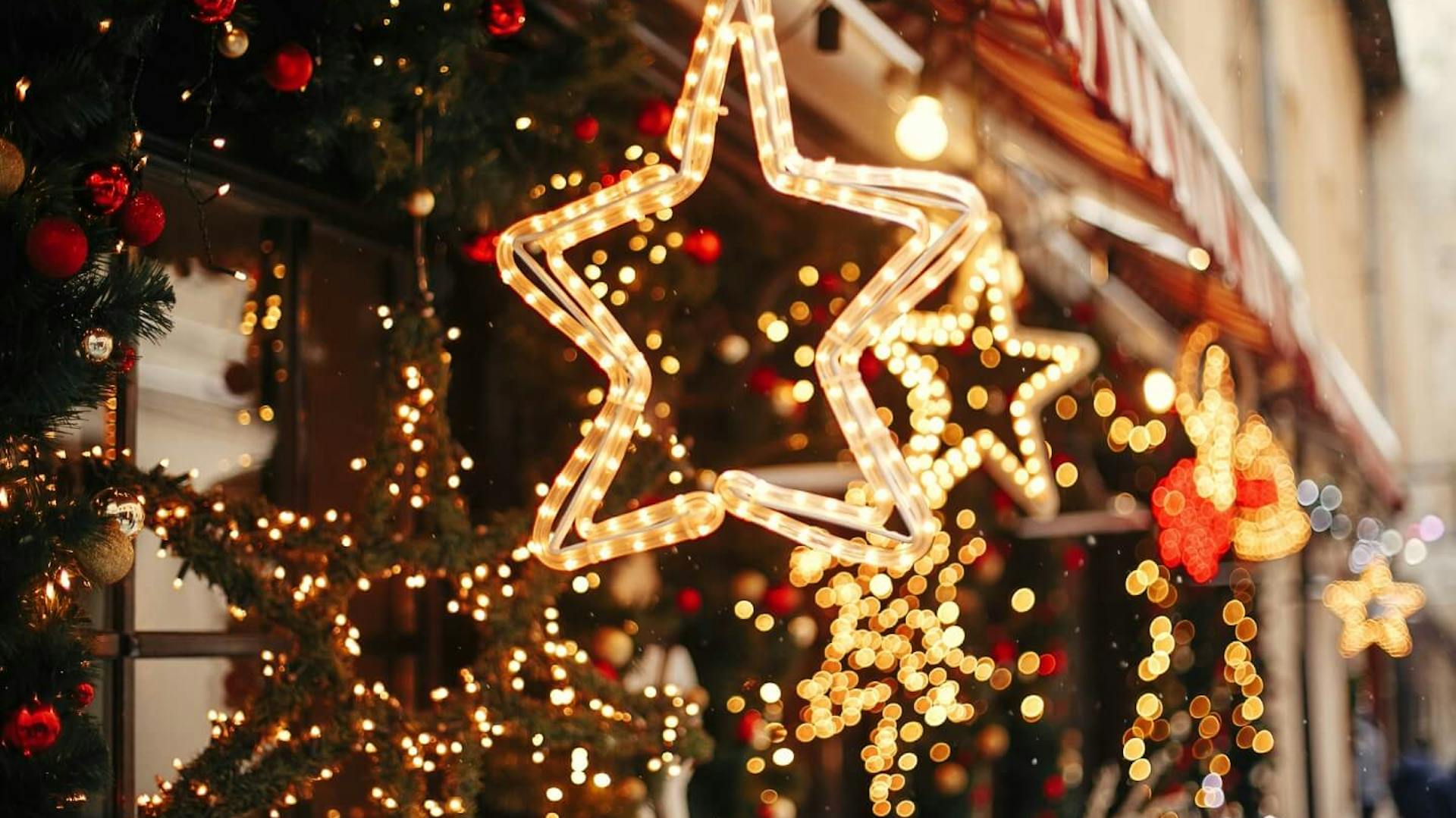 Ghirlande luminose sulla facciata della casa. Sulla tenda da sole sono appese luci a forma di stella.