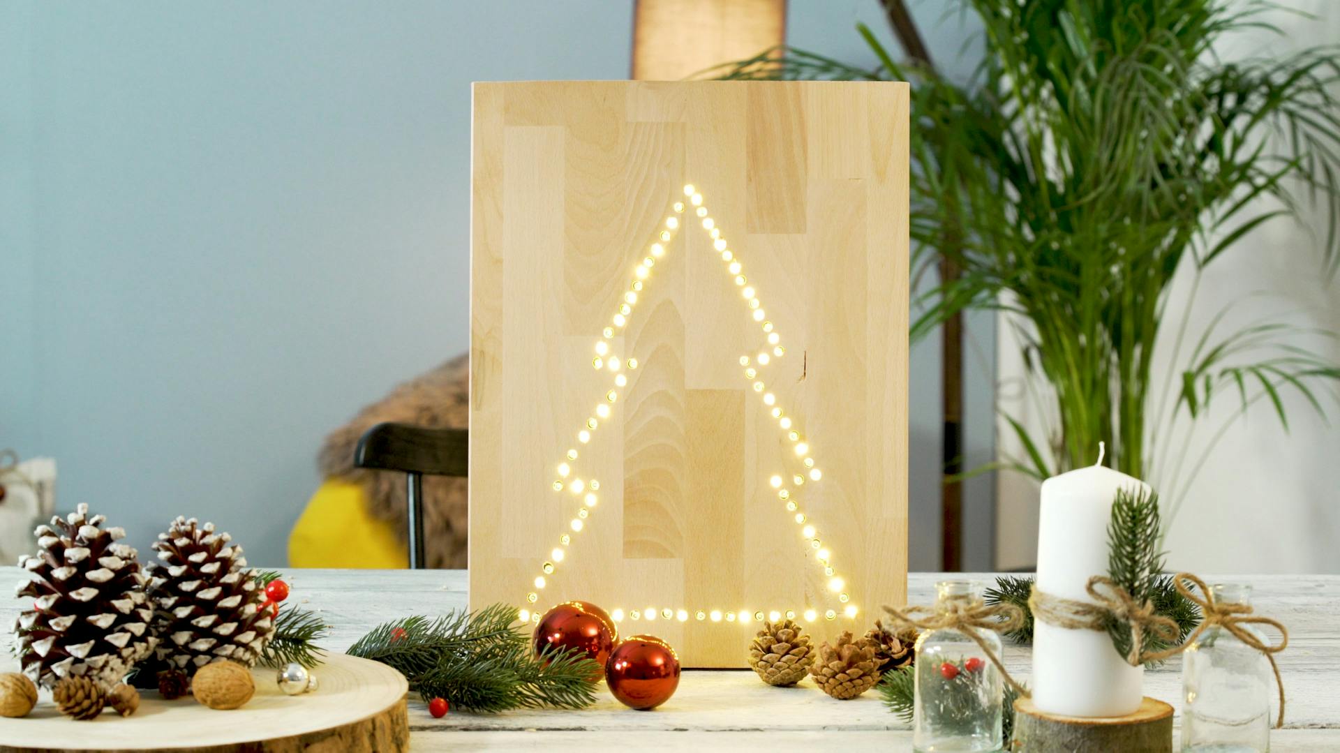 Un quadro con catena luminosa fatto a mano con motivo abete su un’asse di legno.