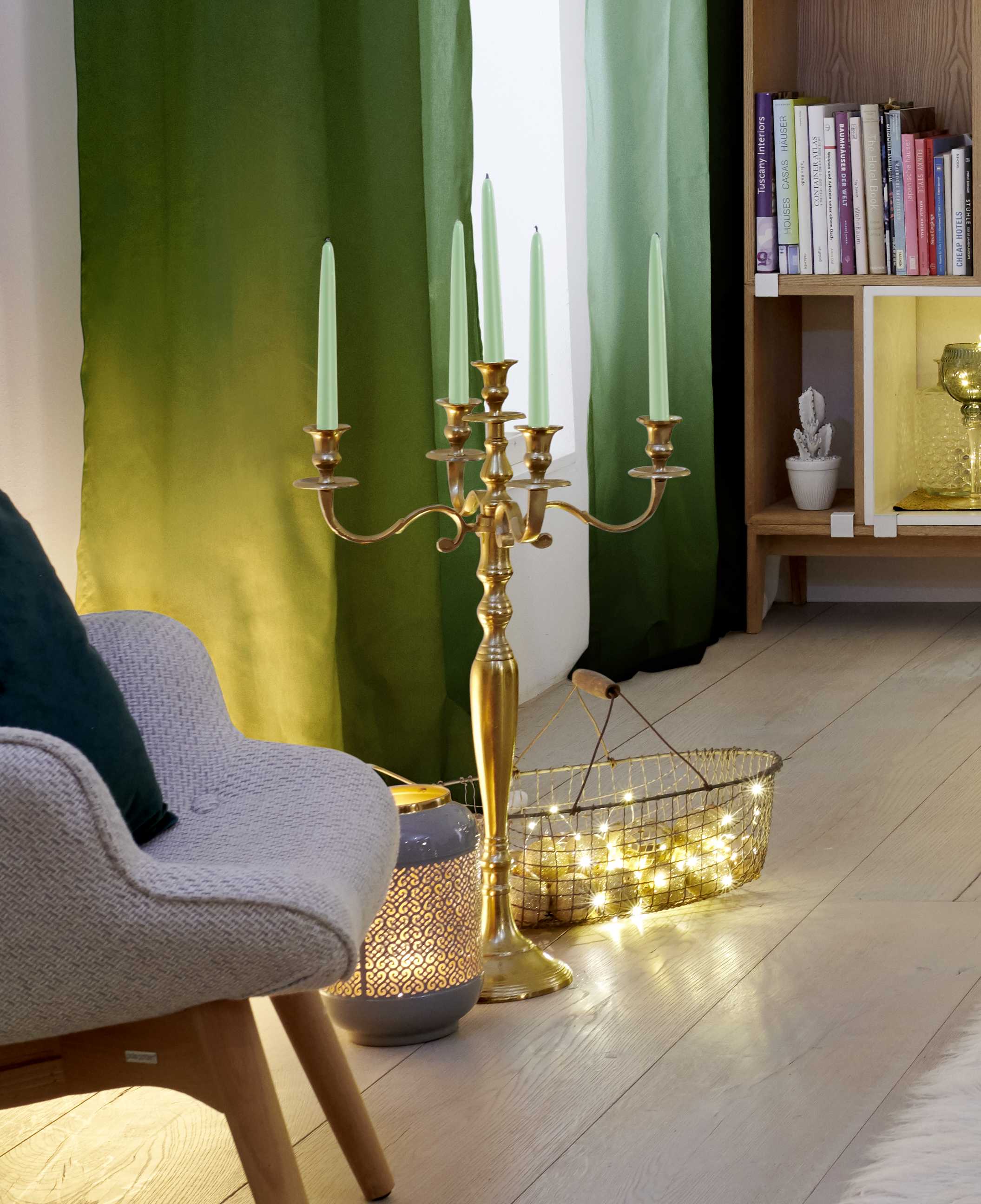 Elegante candeliere dorato con candele verde menta e un cesto con ghirlanda luminosa