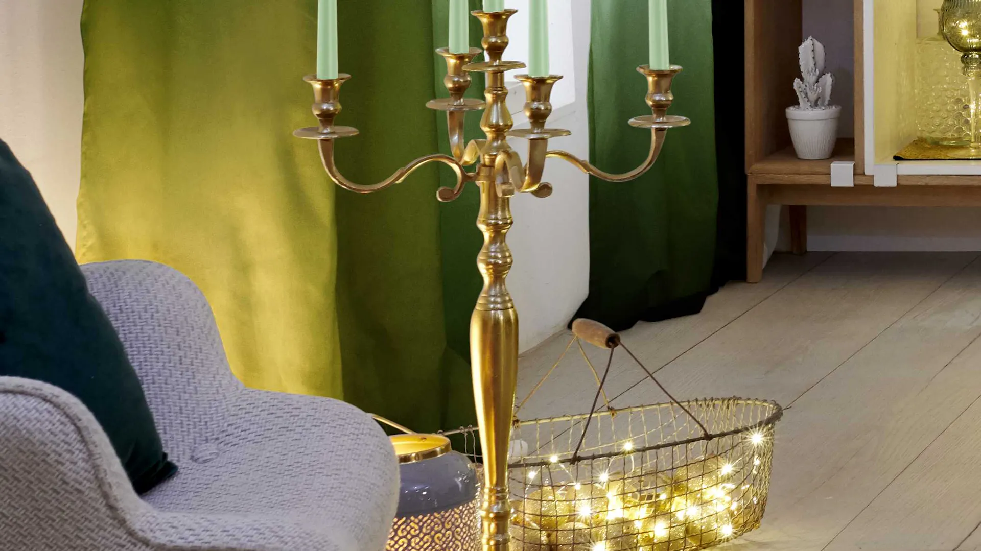 Elegante candeliere dorato con candele verde menta e un cesto con ghirlanda luminosa