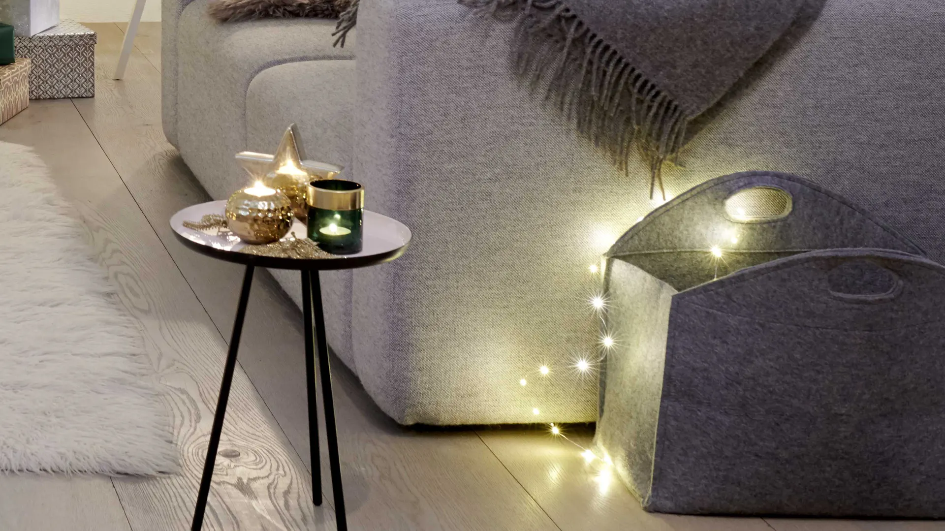 Tavolino da appoggio elegantemente decorato per il Natale con lumicini dorati e verdi e ghirlanda luminosa