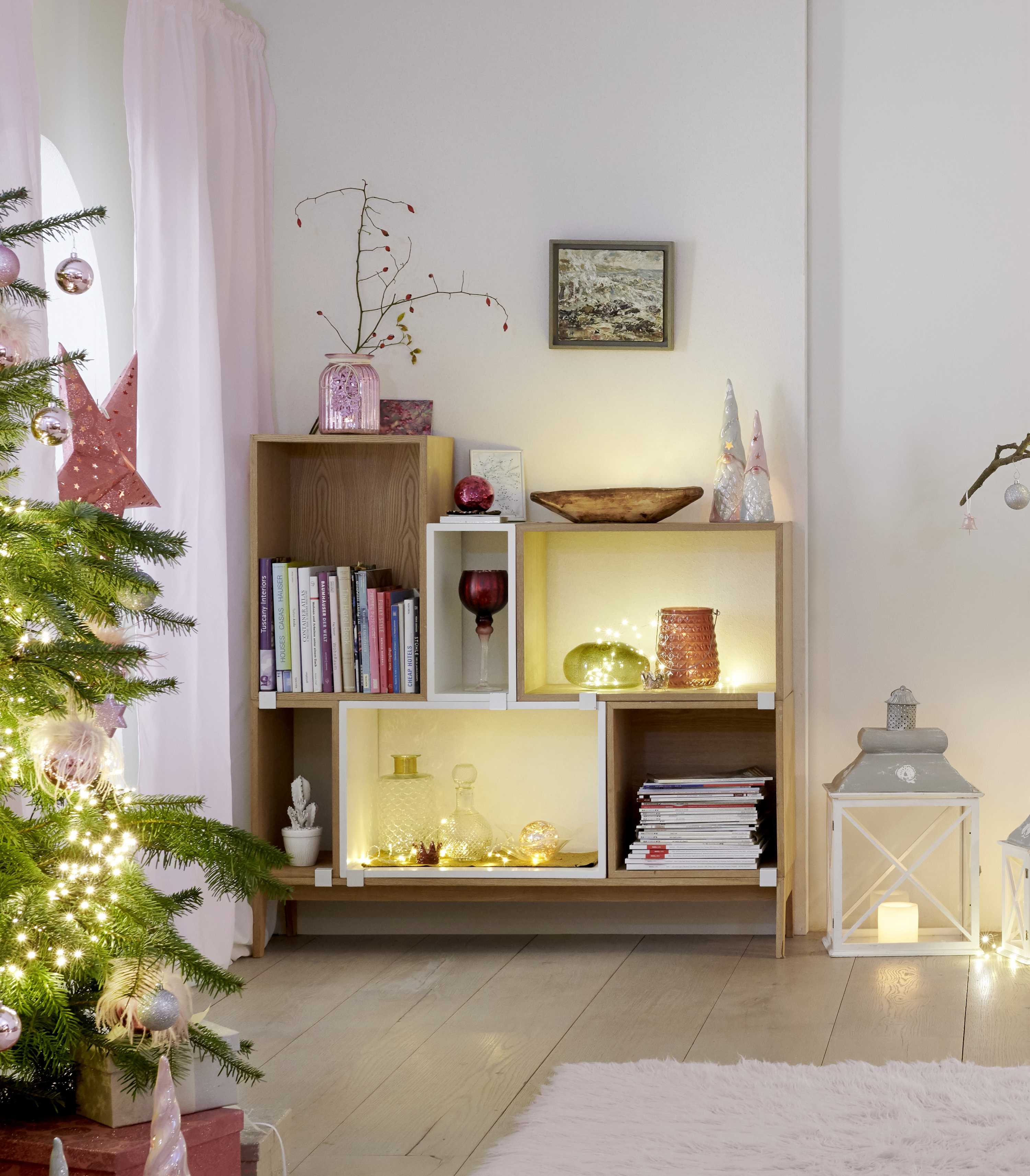 Scaffale con decorazioni natalizie in tonalità pastello con figure di gnomi e ghirlande luminose