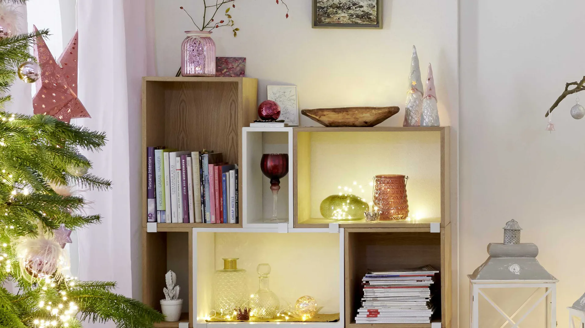 Scaffale con decorazioni natalizie in tonalità pastello con figure di gnomi e ghirlande luminose