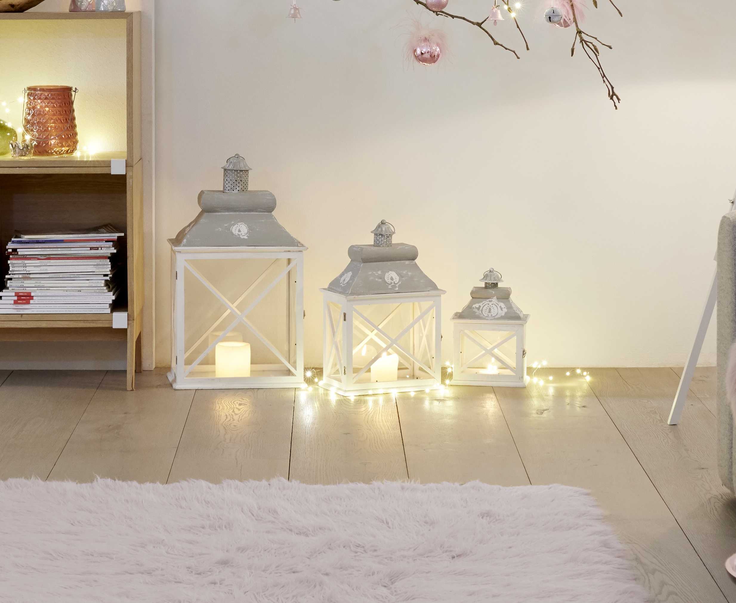 Lanterne bianche come idea per decorazioni natalizie intorno all’albero di Natale