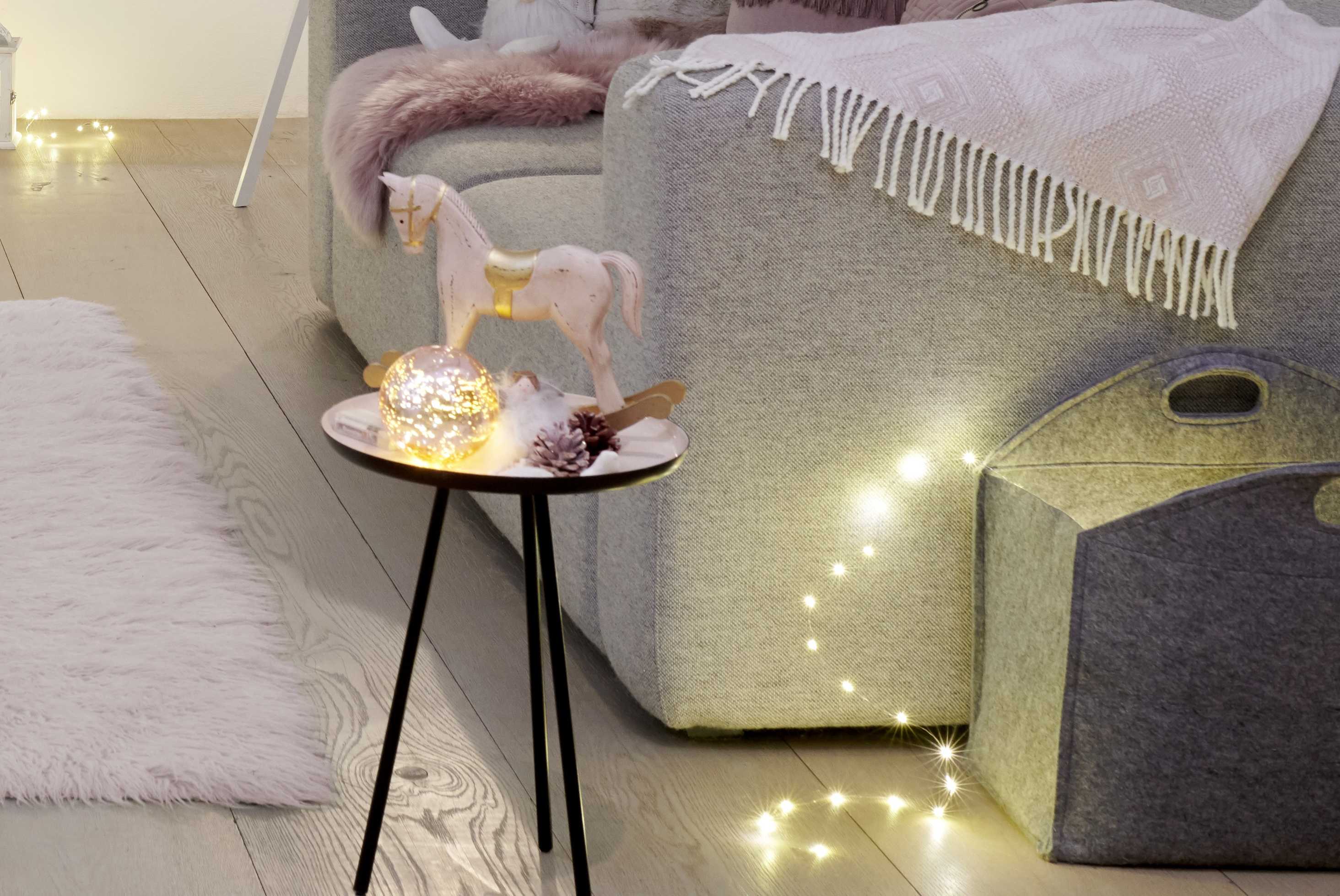 Decorazioni natalizie in rosa tenue: figura decorativa di cavallo a dondolo su un tavolo da appoggio