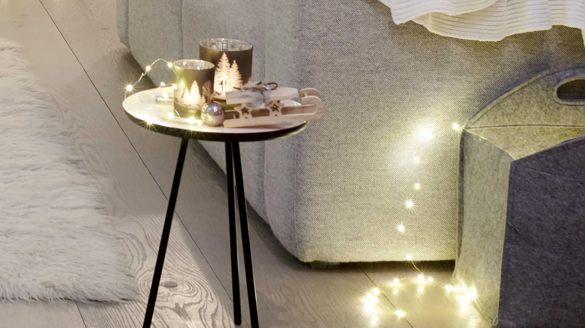 Idea per decorazioni natalizie naturali: figure di legno con ghirlanda luminosa sul tavolo da appoggio