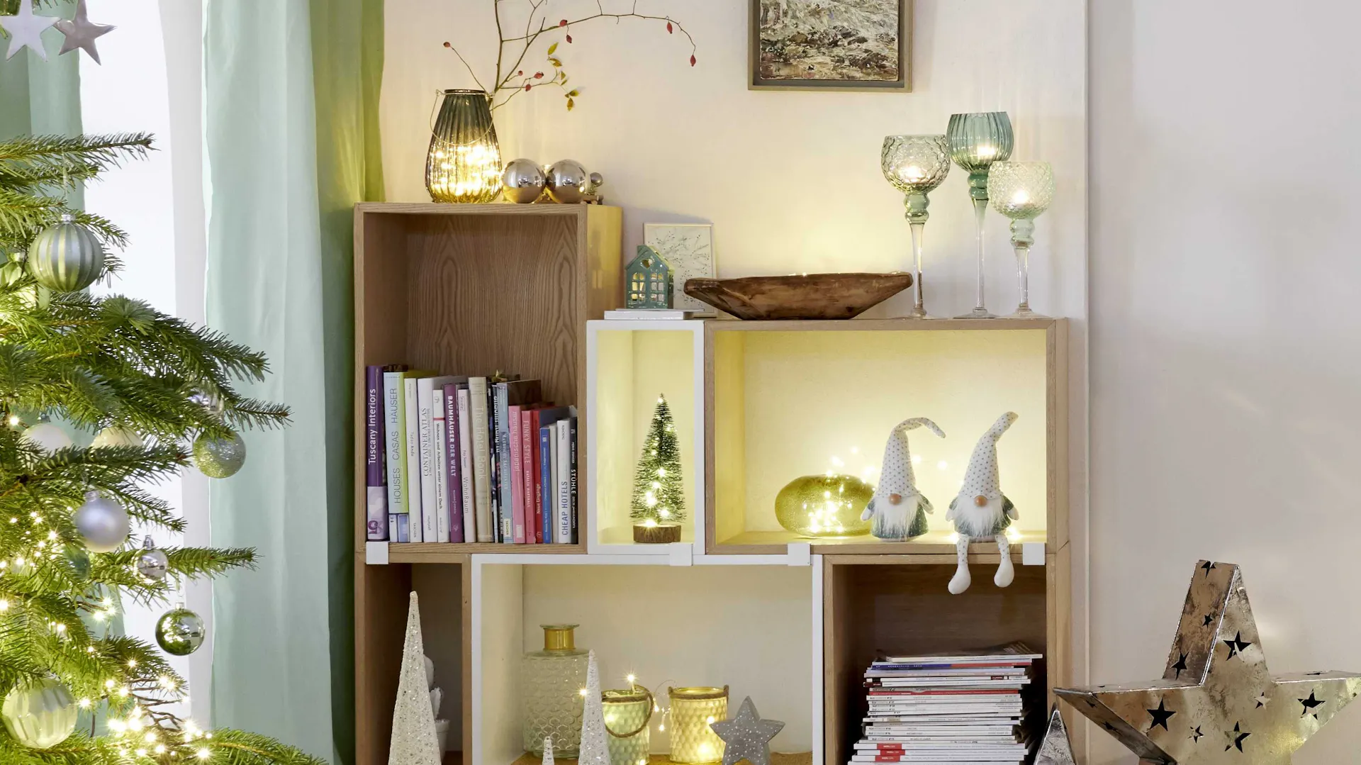 Scaffale per libri con luci, stelle e gnomi come idea per decorazioni natalizie intorno all’albero di Natale