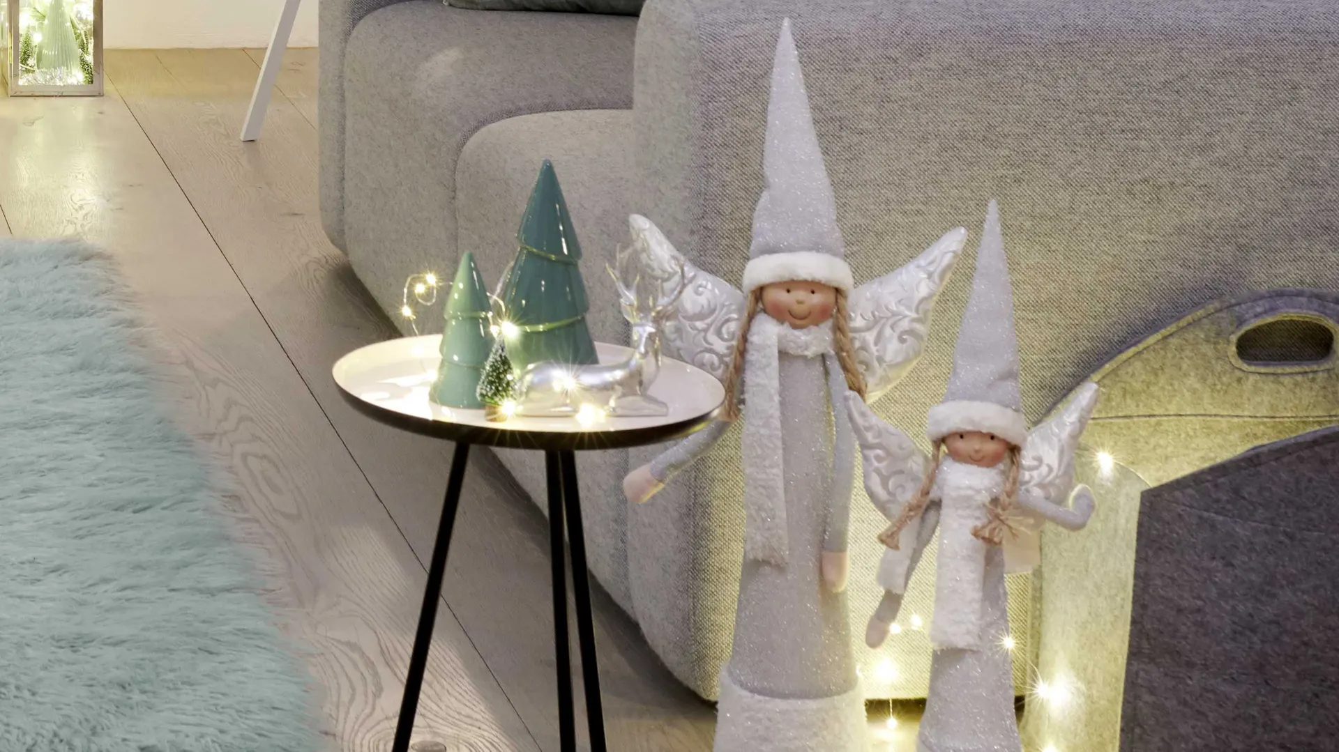 Figure decorative in verde menta su un tavolo da appoggio e delicati angeli per un’elegante e fredda decorazione natalizia