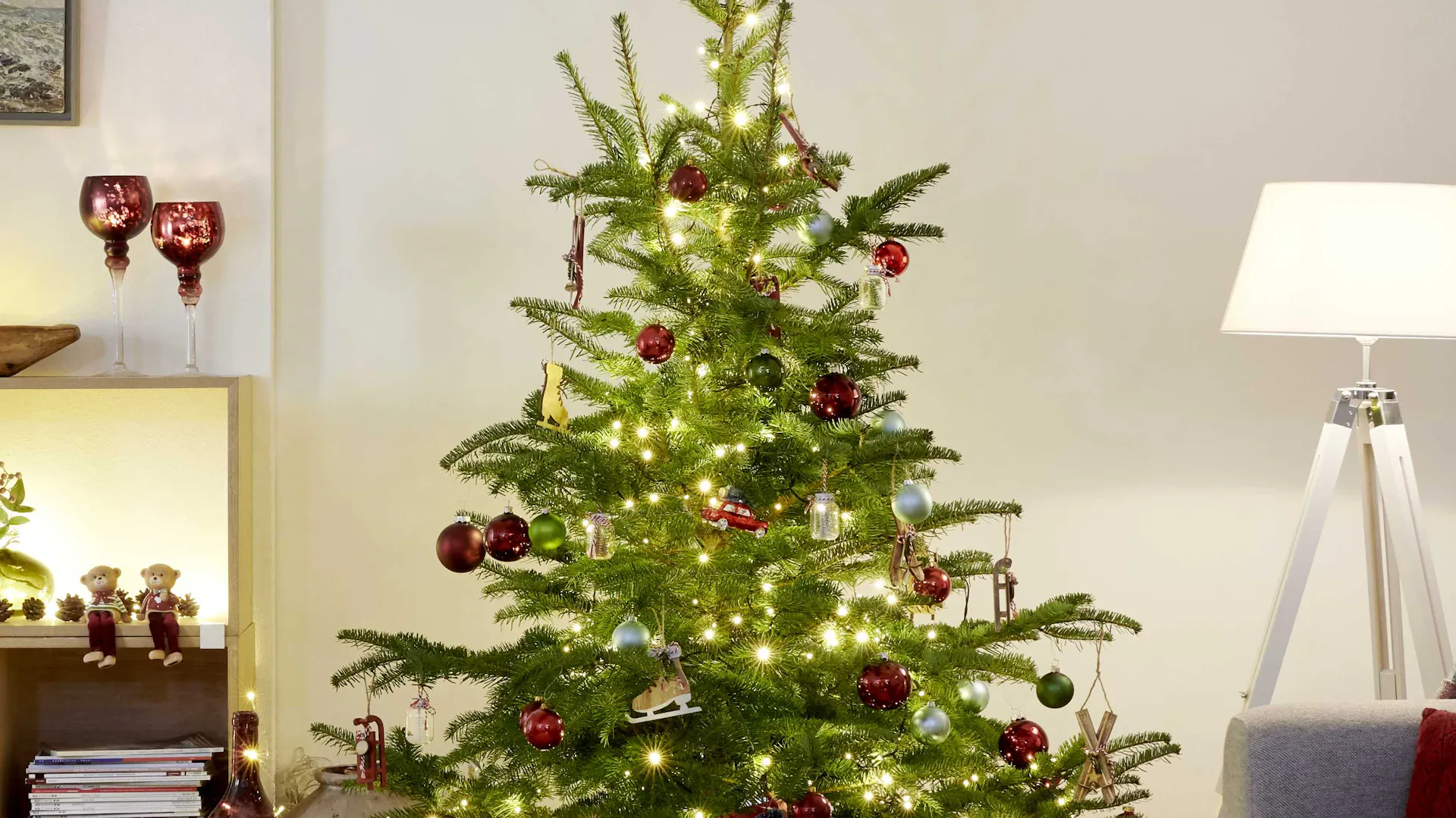 Albero di Natale decorato in modo classico con palline rosse, fiocco rosso e ghirlanda luminosa