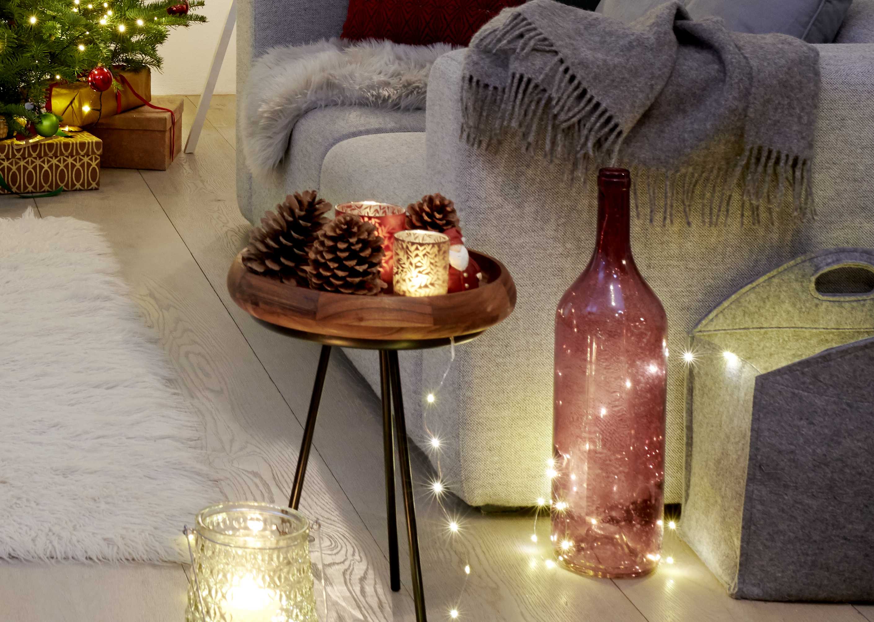 Tavolo da appoggio con lumicino e grandi pigne come decorazione natalizia