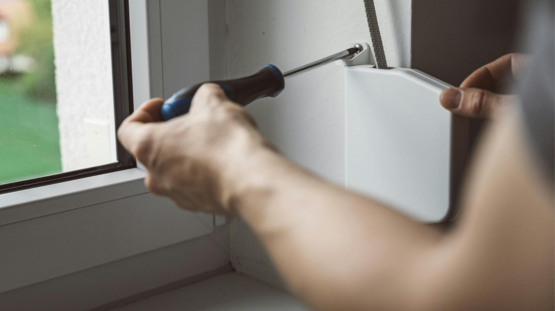 Person schraubt alten manuellen Gurtwickler ab.