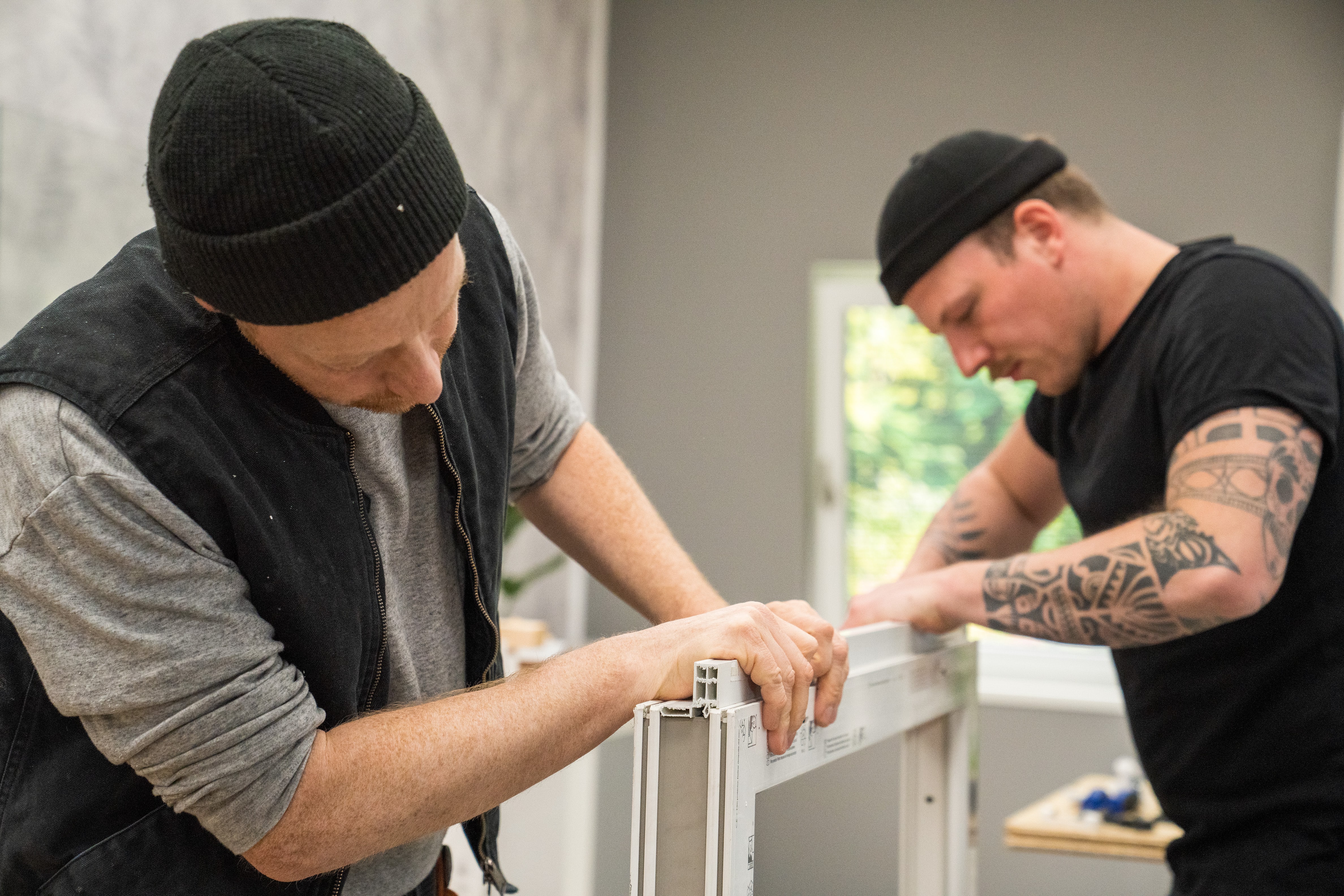 Handwerker bringen ein Fensterbankprofil am Rahmen an.