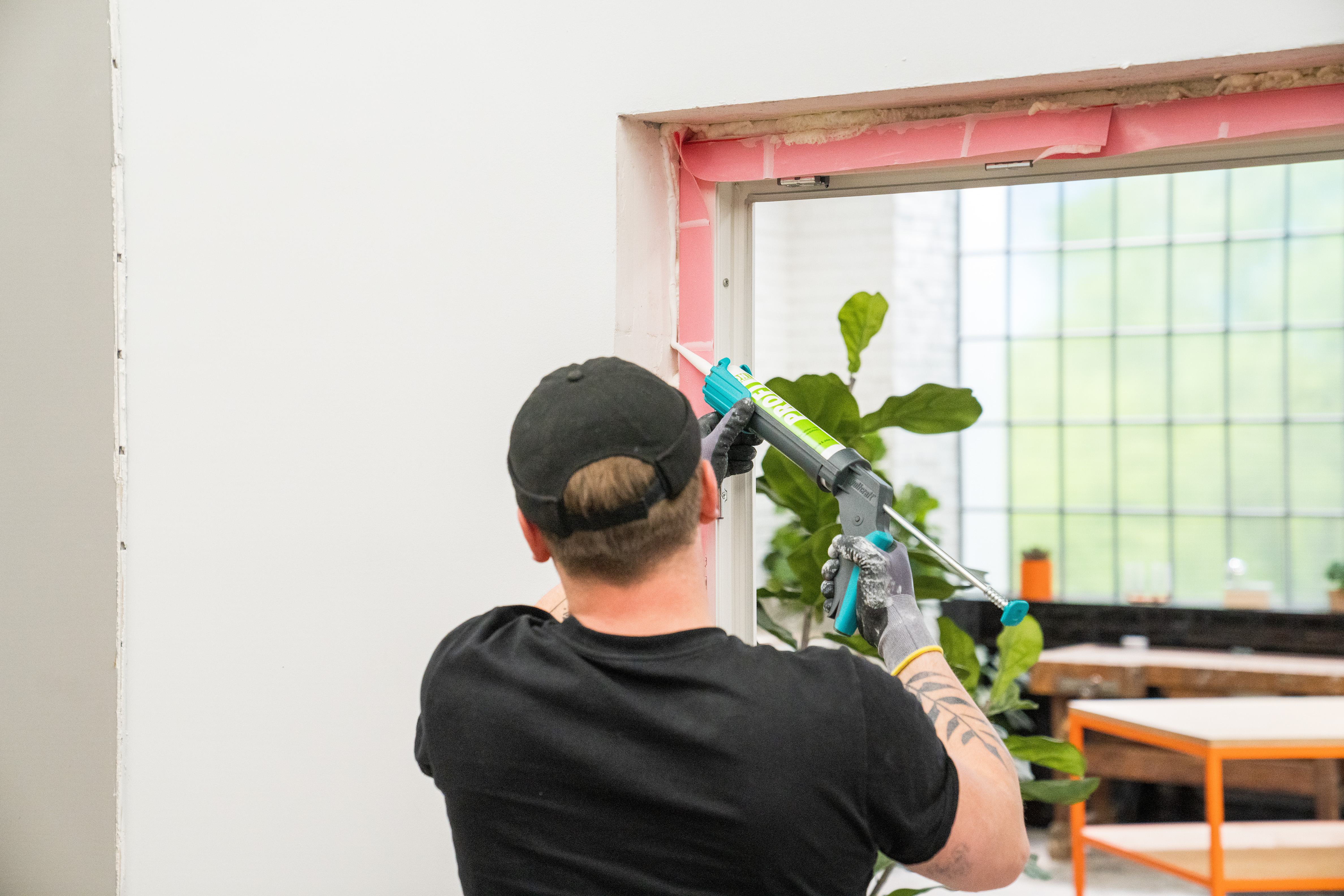 Handwerker trägt mit einer Kartuschenpistole Folienkleber auf.