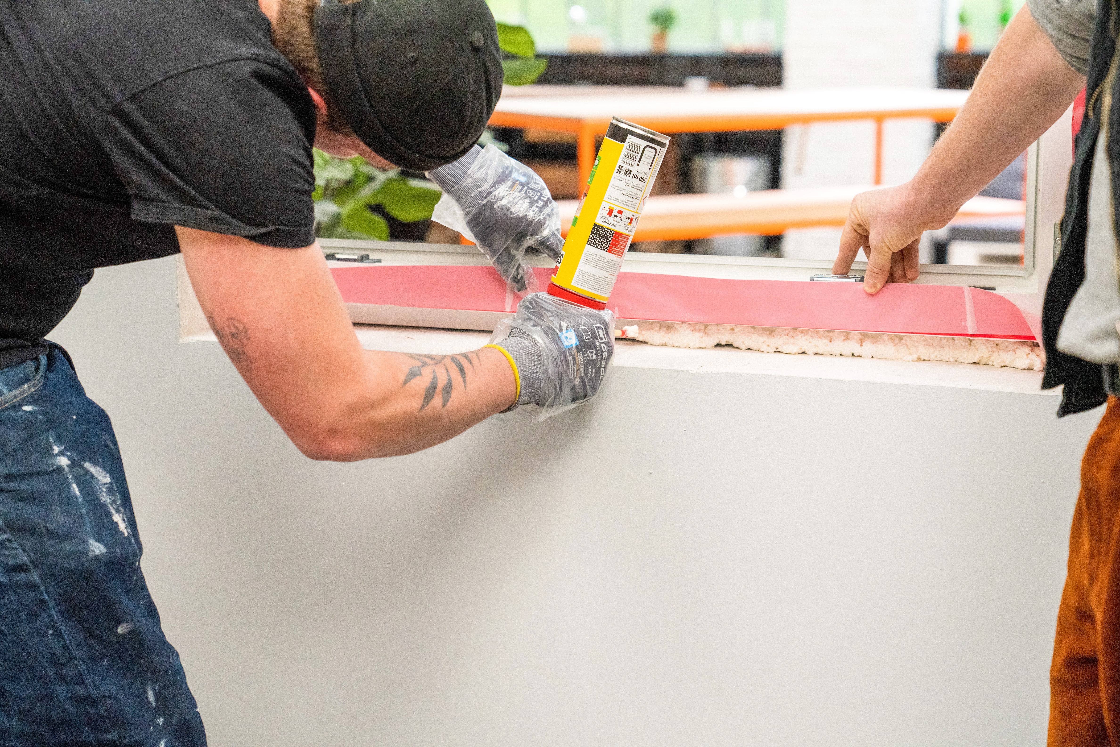 Handwerker schäumt die Fuge zwischen Fenster und Mauerwerk aus.
