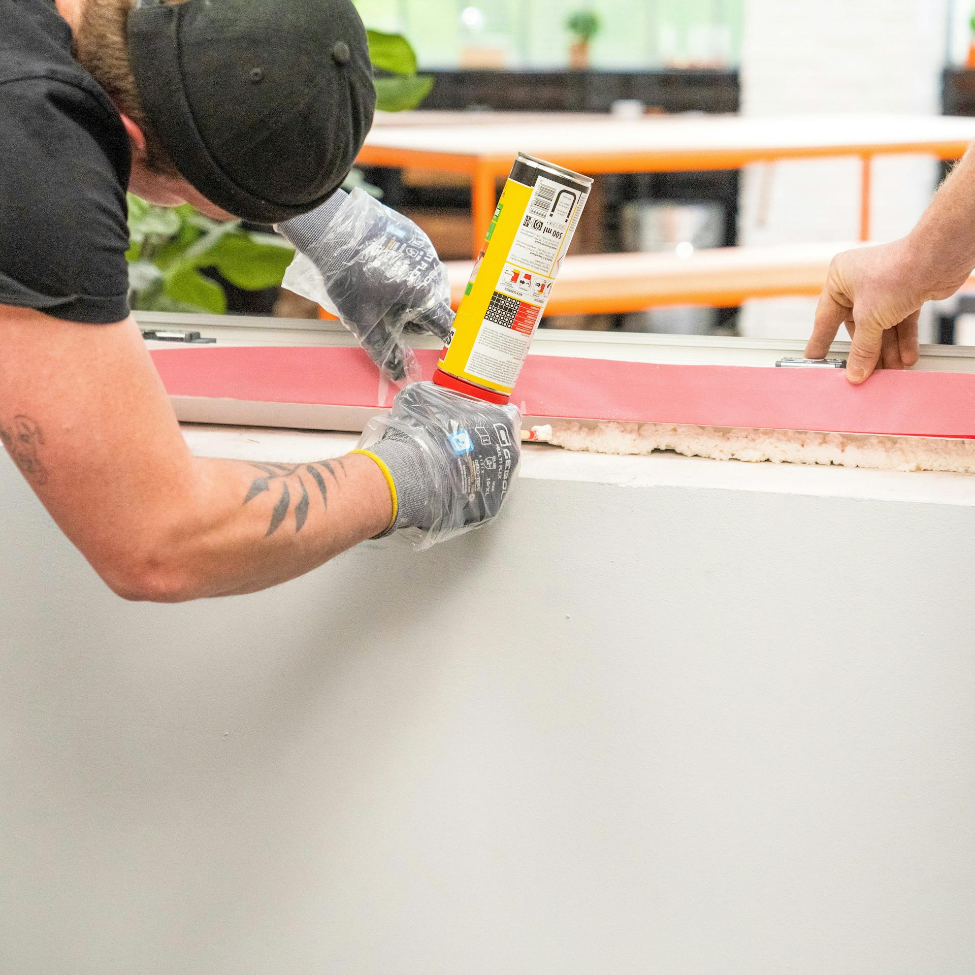 Handwerker schäumt die Fuge zwischen Fenster und Mauerwerk aus.