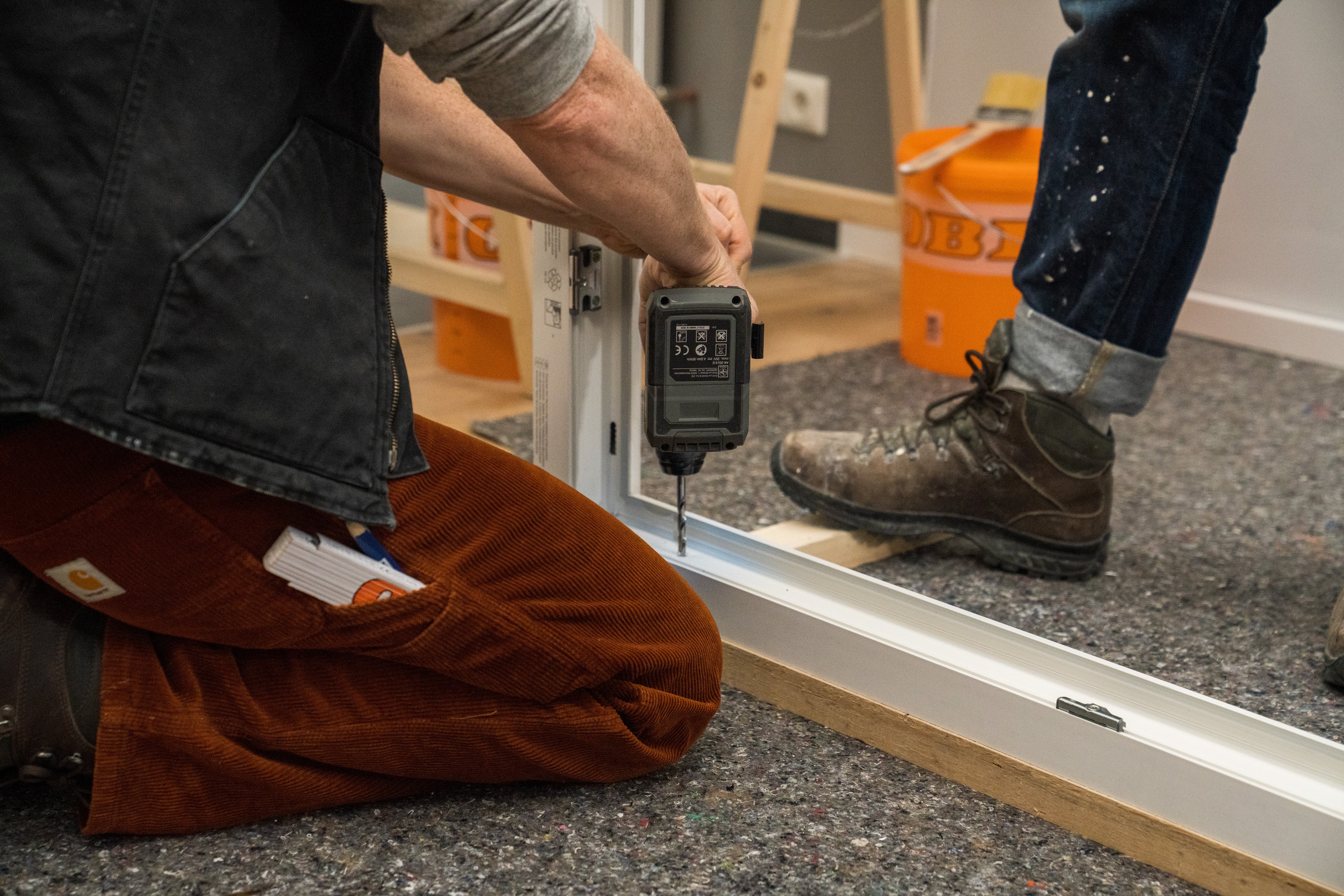 Handwerker schraubt Löcher in den Fensterrahmen.