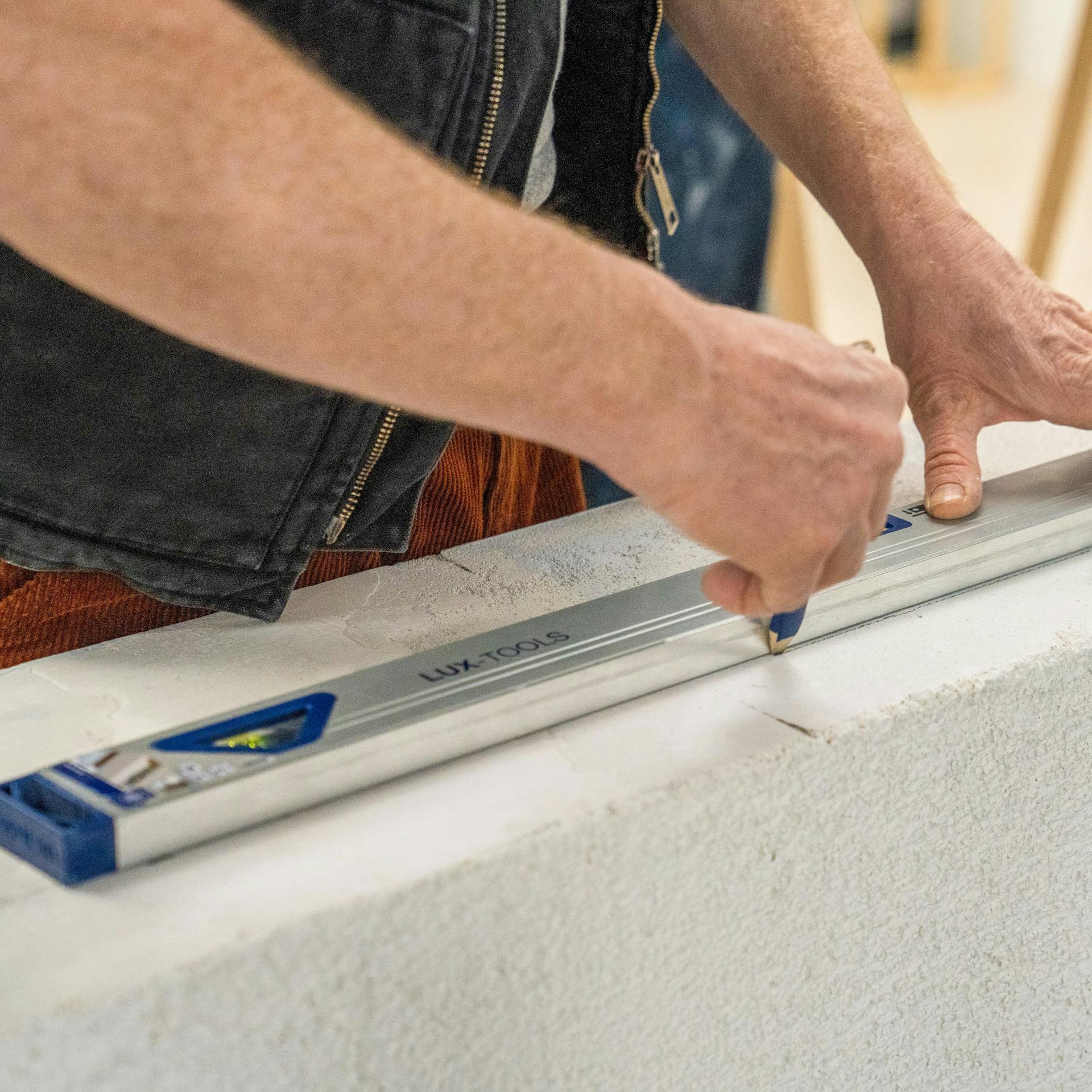 Handwerker markiert die Position des Fensters in der Laibung.